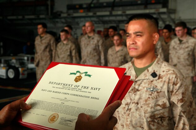 Hospital Corpsman 2nd Class Wendell Tabios, hospital corpsman, Command Element, 15th Marine Expeditionary Unit, stands at the position of attention before being awarded the Navy and Marine Corps Commendation Medal during the Command Element’s promotion and awards ceremony in the hangar bay of the USS Peleliu, Dec. 1. Tabios received the award for his immediate medical response after a head-on collision on Camp Pendleton in July, where he saved a life. The 15th MEU is deployed as part of the Peleliu Amphibious Ready Group as a U.S. Central Command theater reserve force, providing support for maritime security operations and theater security cooperation efforts in the U.S. 5th Fleet area of responsibility. Tabios, 37, is from Cavite, Philippines. (U.S. Marine Corps photo by Cpl. John Robbart III/Released)