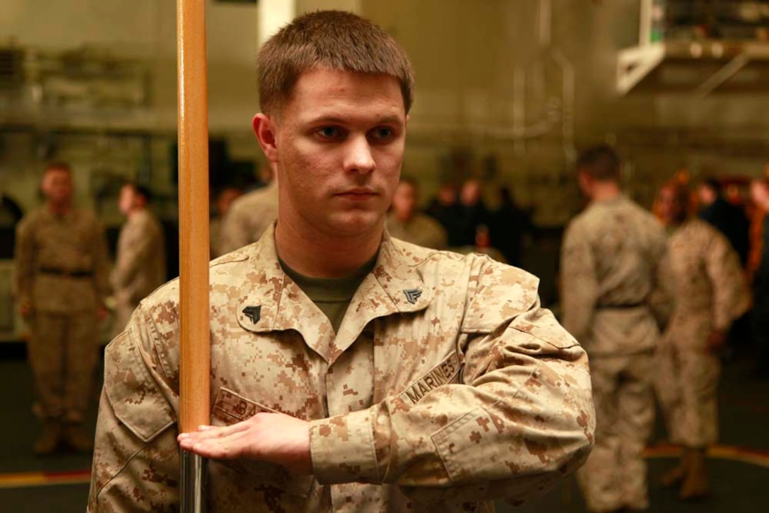 Corporal Wesley A. Barrett, scout observer, Command Element, 15th Marine Expeditionary Unit, practices guidon manual in the hangar bay of the USS Peleliu during Corporal's Course, Dec. 3. Corporals' Course is a professional military education for enlisted Marines designed to give them the tools to become better effective small unit leaders. The 15th MEU is deployed as part of the Peleliu Amphibious Ready Group as a U.S. Central Command theater reserve force, providing support for maritime security operations and theater security cooperation efforts in the U.S. 5th Fleet area of responsibility. Barrett, 21, is form Wood River, Ill. (U.S. Marine Corps photo by Cpl. John Robbart III)