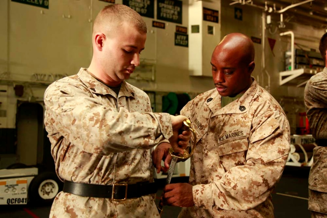 Gunnery Sgt. Jason E. Barnes, chief instructor and supply chief, Command Element, demonstrates the proper way to return sword to Cpl. Nicholas B. Watson, radar technician, Marine Medium Helicopter Squadron 364 (Rein.), both with 15th Marine Expeditionary Unit, in the hangar bay of the USS Peleliu during Corporal's Course, Dec. 3. Corporals' Course is a professional military education for enlisted Marines designed to give them the tools to become better effective small unit leaders. The 15th MEU is deployed as part of the Peleliu Amphibious Ready Group as a U.S. Central Command theater reserve force, providing support for maritime security operations and theater security cooperation efforts in the U.S. 5th Fleet area of responsibility. Barnes, 33, is from Baton Rouge, La., and Watson, 25, is from Midland, Mich. (U.S. Marine Corps photo by Cpl. John Robbart III)