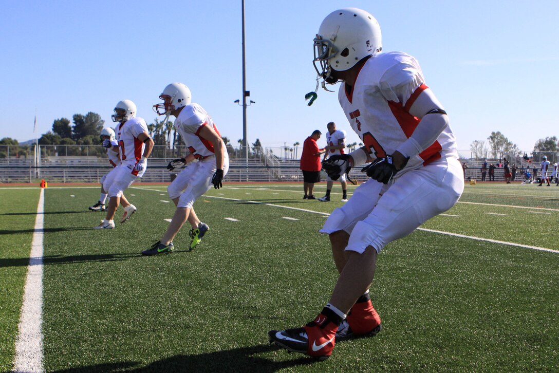 Players perform a back-peddle agility exercise during pregame warm-ups at the 2012 Best of the West Football Championship. Bragging rights went to Camp Pendleton's Marine Logistics Group football team after defeating 29 Palms' MLG team by a score of 28 - 0 here Dec. 8. With the win, Pendleton's MLG team, known as 'the Beast', claimed the Western Division All-Star Football Title for the third time in four years.