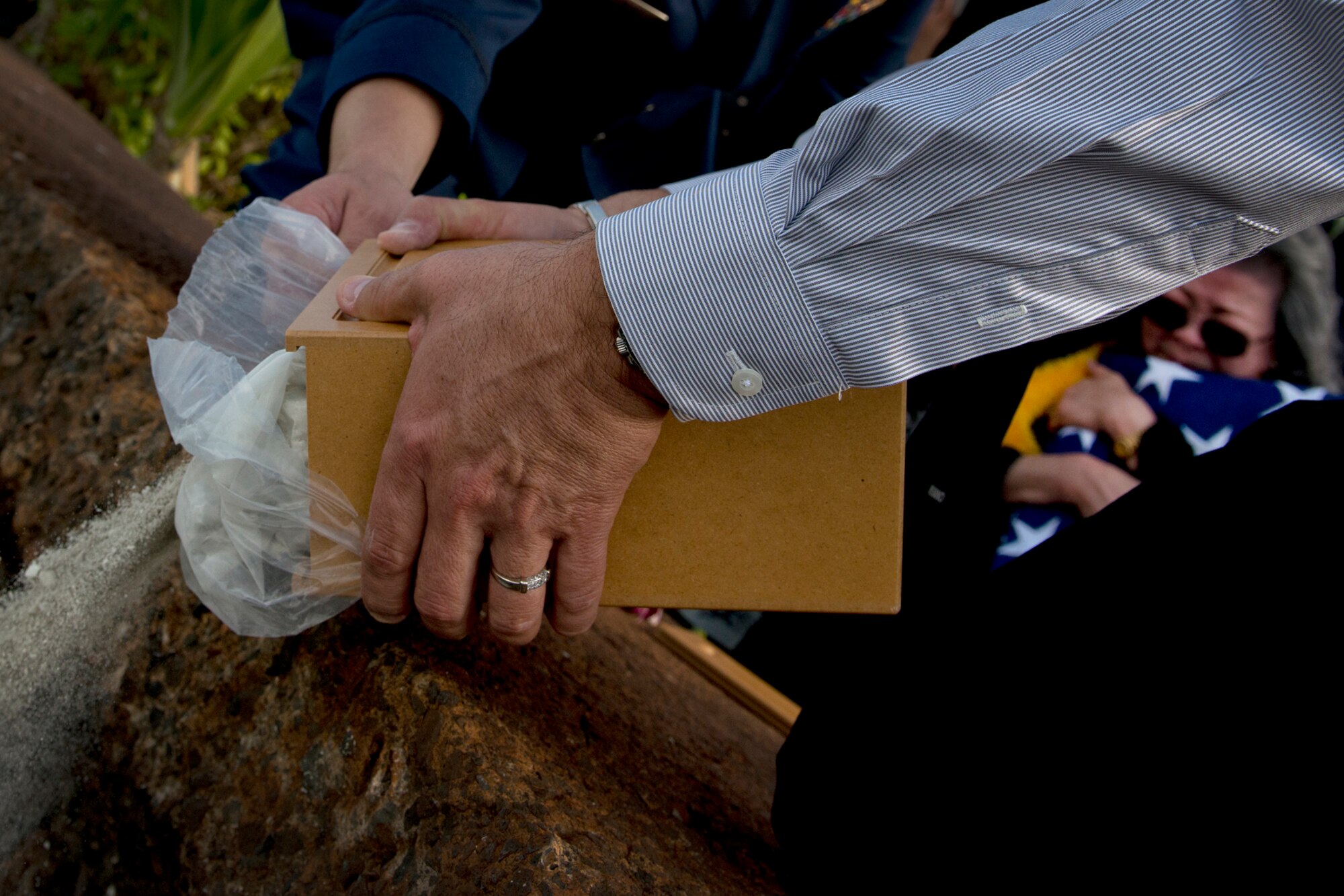 Bill Perry, son of Senior Master Sgt. (Ret.) Raymond Perry, is assisted by Capt. Andrew Stewart, 15th Wing commander’s action group, to spread the ashes of his late father during a ceremony Dec. 7, 2012 at Joint Base Pearl Harbor-Hickam, Hawaii. Perry was a Dec. 7, 1941, Hickam Field attack survivor whose wishes were for his family to return him to Hickam and spread his ashes. He served 26-years in the Air Force and was a founding member of the pararescue career field. He returned to Hickam and serve for more than 20 years as a fire inspector for the Hickam fire department. This is the first time a Hickam Field survivor has had their remains scattered at Hickam Field. He is the first among Hickam Field survivors to have his ashes spread at Hickam. Perry’s widow, Elizabeth Chew Perry, clutches the flag in the background she was presented by base leadership. (U.S. Air Force photo/Staff Sgt. Mike Meares)