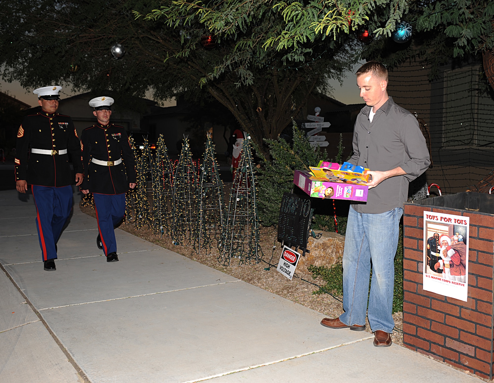 U.S. Air Force 1st Lt. Joshua Palochak, 41st Electronic Combat Squadron, waits to hand toys to two of the U.S. Marine Corps Marines organizing the Marine Toys for Tots Foundation drive in Tucson, Ariz., Dec. 1, 2012. Palochak used a computer program to set his Christmas lights to blink in rhythm with the music played by a local radio station. (U.S. Air Force photo by Senior Airman Timothy Moore/Released)