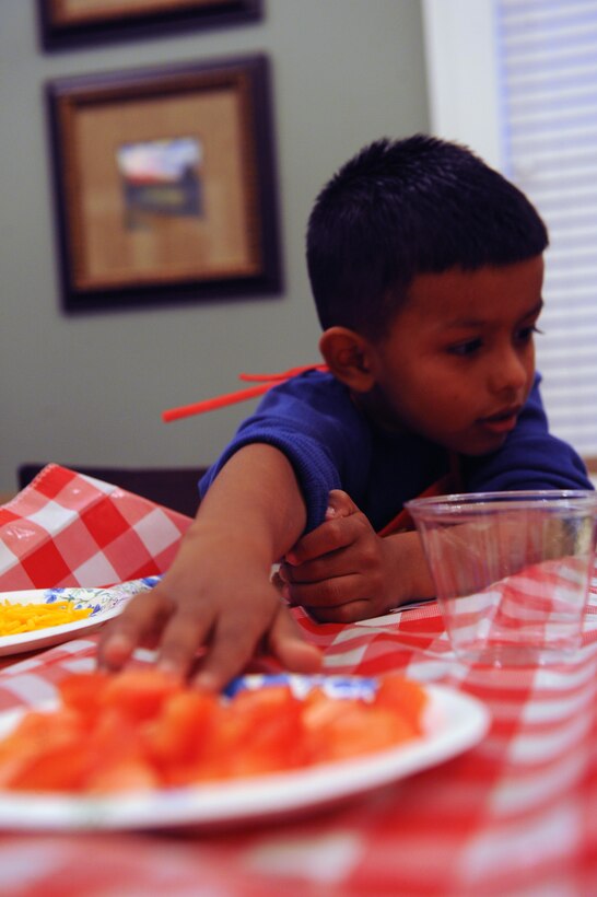 Alex, 5, reaches for lettuce to make his burrito face during the Kids in the Kitchen on Monday at the McHugh Woods Community Center. The Exceptional Family Member Program and Families Over Coming Under Stress joined to show the children how to talk about their feelings with burrito making.