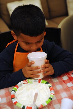 Alex, 5, looks at his food coloring before dumping it into his play dough during the Kids in the Kitchen on Monday at the McHugh Woods Community Center. The Exceptional Family Member Program and Families Over Coming Under Stress combined their efforts to teach the children how to make homemade play dough.