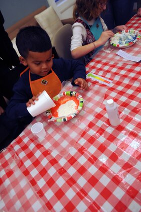 Alex, 5, pours food coloring into flour to make play dough during the Kids in the Kitchen on Monday at the McHugh Woods Community Center. The Exceptional Family Member Program and Families Over Coming Under Stress combined their efforts to teach the children how to make homemade play dough.