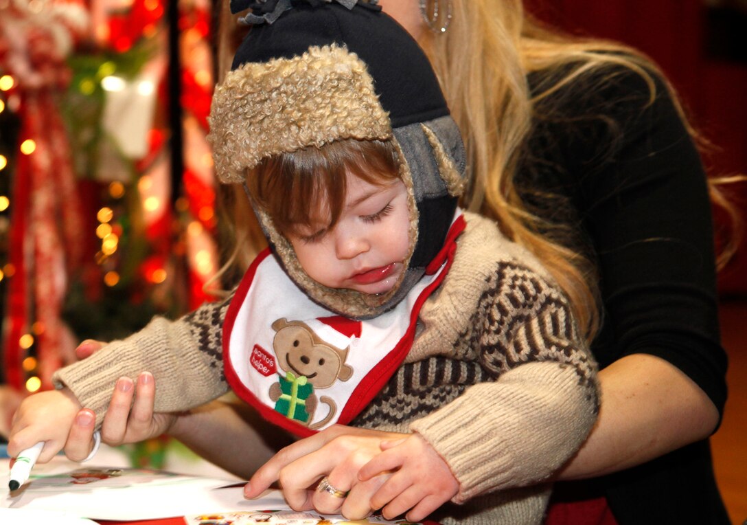 A toddler draws a picture at the Marine Corps Base Camp Lejeune Headquarters and Support Battalion Holiday Jubilee at the Goettge Field House Dec. 6. There were many family-friendly events to partake in, including a face-painting station and a drawing table, an area to get pictures taken, and a clown who blew up animal balloons for children. 