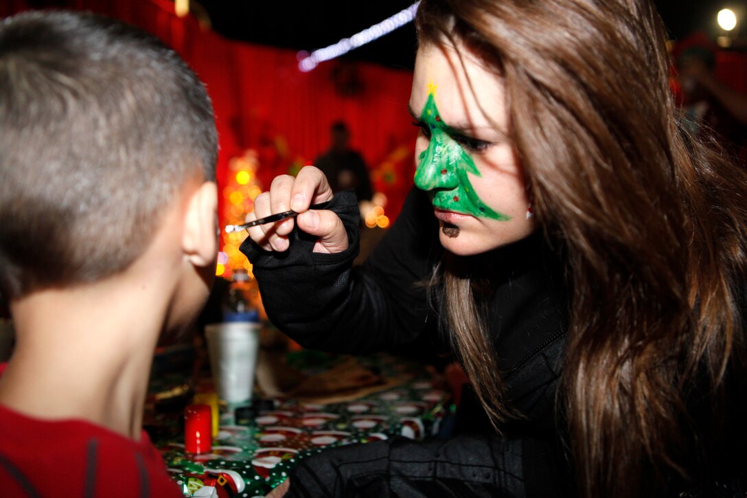 Lance Cpl. Jan Jumonville, a volunteer for the Marine Corps Base Camp Lejeune Headquarters and Support Battalion Holiday Jubilee, paints a child’s face during the event at the Goettge Field House Dec. 6. Face-painting was one of the many activities at the event, but it was one of the most popular choices among the children at the party.