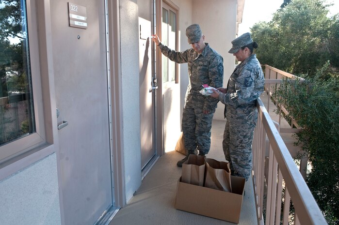 Senior Master Sgt. Kara Barcomb, 99th Logistics Readiness Squadron first sergeant, and Master Sgt. Sacha Martinez, 99th LRS quality assurance superintendent, deliver cookies to a dorm resident during the Cookie Drive Dec. 11, 2012, at Nellis Air Force Base, Nev. The final number of donated cookies reaches 1,200 dozen. (U.S. Air Force photo by Staff Sgt. Christopher Hubenthal)