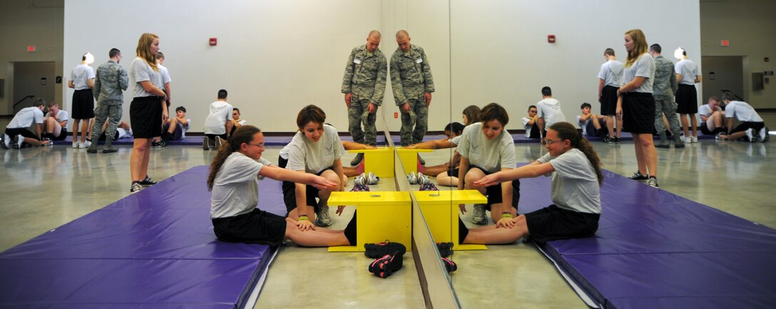 Airman 1st Class Dustin Brown, 375th Communications Support Squadron and volunteer, assist Mascoutah High School Junior ROTC students during the flexibility portion of their quarterly physical training test Dec. 5. (U.S. Air Force photo/Staff Sgt. Stephenie Wade)