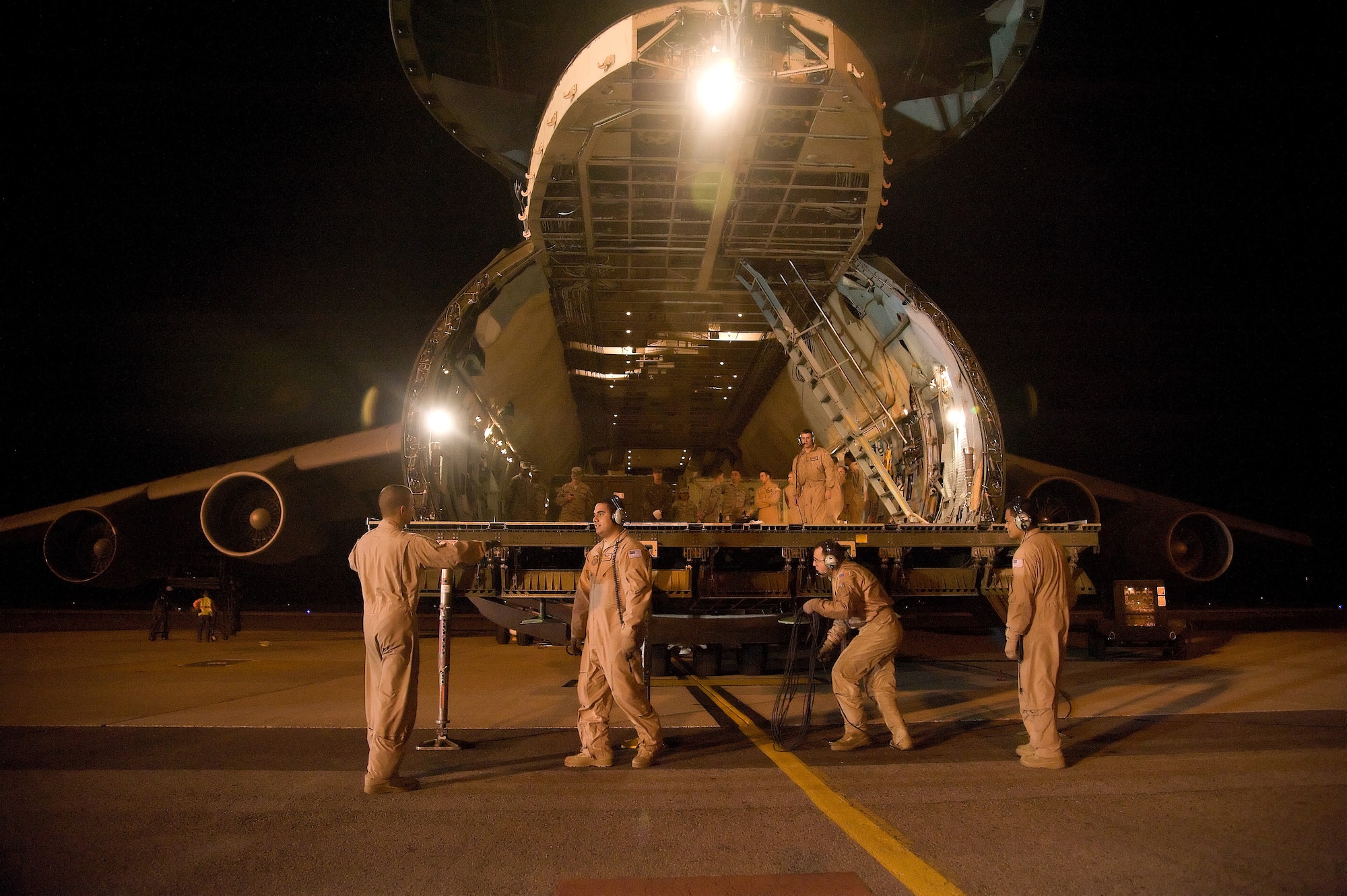 Four loadmasters work to position stabilizing jacks under the nose loading ramp of a C-5 Galaxy from the 60th Air Mobility Wing, Travis AFB, Calif., in preparation of cargo off-load operation at Dover AFB, Del. Dec. 4, 2012. The aircraft completed a mission in support of Operation Enduring Freedom.  (U.S. Air Force photo by Greg L. Davis)