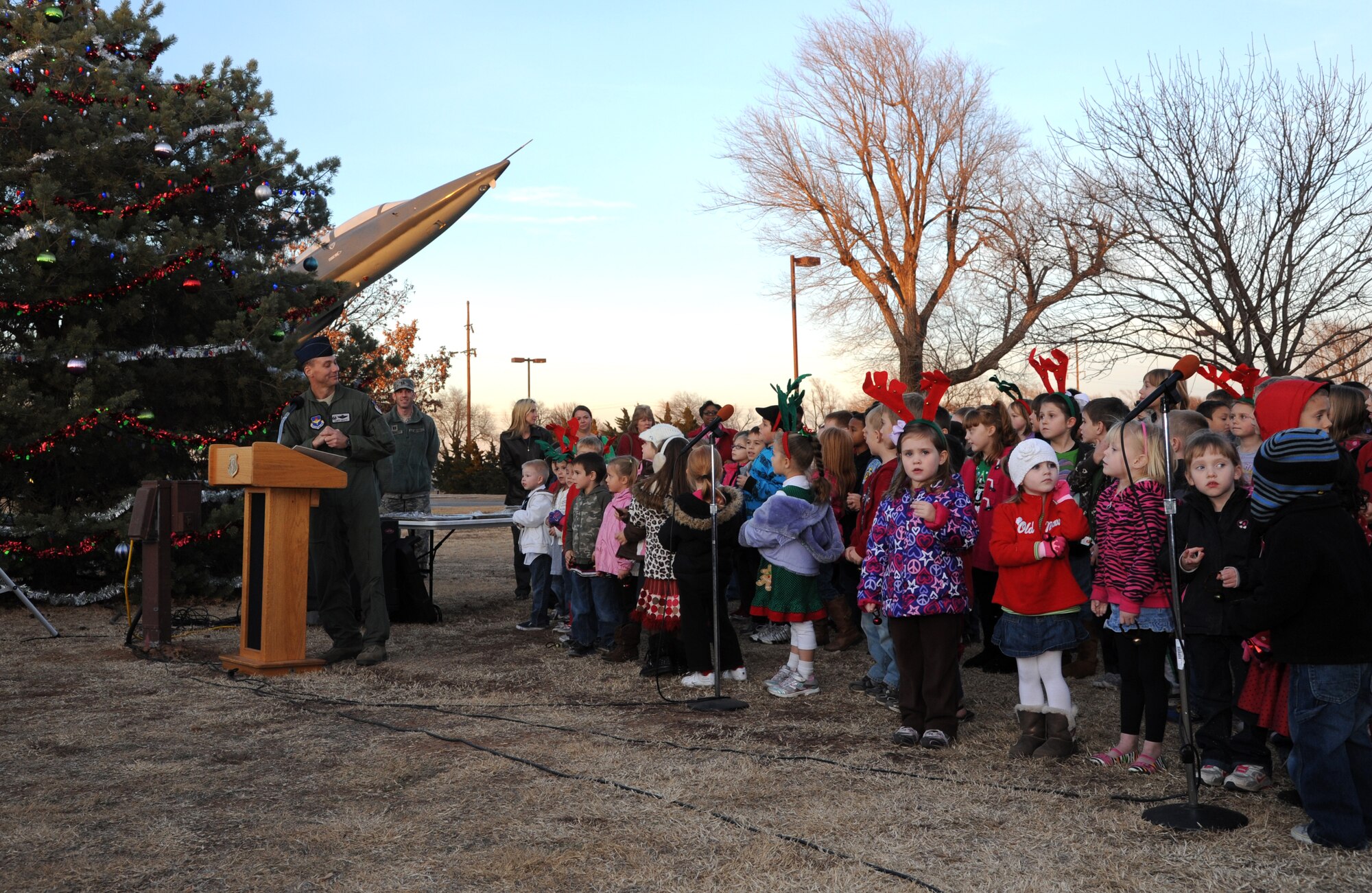 Col. James Abatti, the 71st Operations Group commander, at podium, introduces the 37 member choir from Eisenhower Elementary School at Vance Air Force Base, Okla. The children sang several holiday songs during the Vance Christmas Tree lighting ceremony held Dec. 5. (U.S. Air Force photo/ Airman 1st Class Frank Casciotta) 