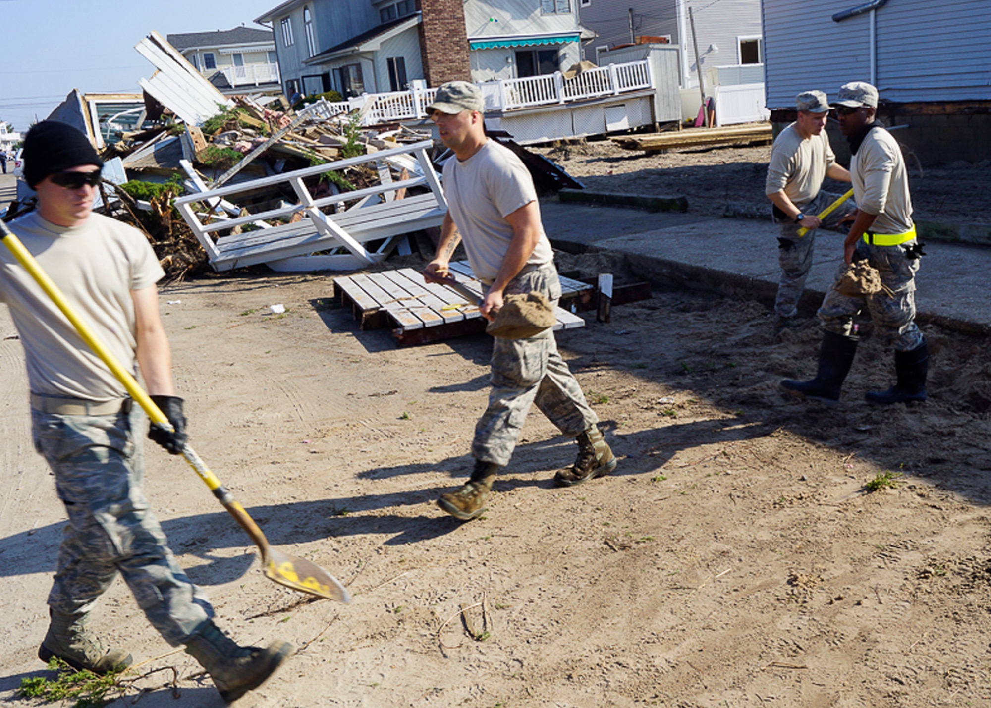 From left, Senior Airman Daniel Propper, Tech. Sgt. William Cox, Senior Airman Jonathan Joshua and Senior Airman James Porter, 11th CES water and fuel systems maintenance technicians,  transport dirt to cover a hose that was laid in the street for pumping storm surge water from a residential area in Breezy Point, N.Y., Nov. 10, 2012. The 11th CES team deployed to N.Y., to provide assistance to Hurricane Sandy relief efforts. (U.S. Air Force photo/Tech. Sgt. Eddie White) 