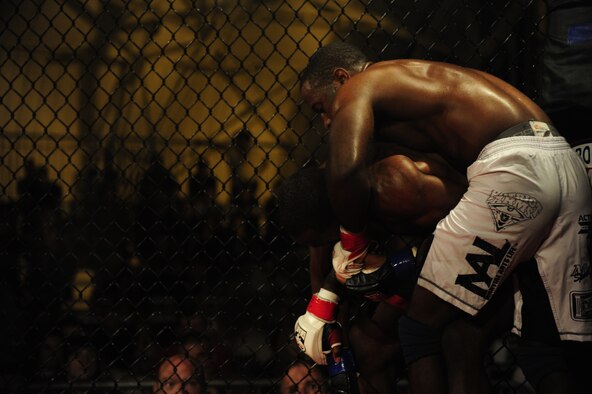 Staff Sgt. Steve Burks, an avionics Airman of 1st Special Operations Aircraft Maintenance Squadron, presses his opponent, Michael Roberts, against a cage in the co-main event at Strike Fight at Hanger 102 at Eglin Air Force Base, Fla., Dec. 8.  Burks utilized his wrestling skills throughout the match and continued to press Roberts against the cage in an attempt to tire him.  (U.S. Air Force Photo / Airman 1st Class Benjamin D. Kim)