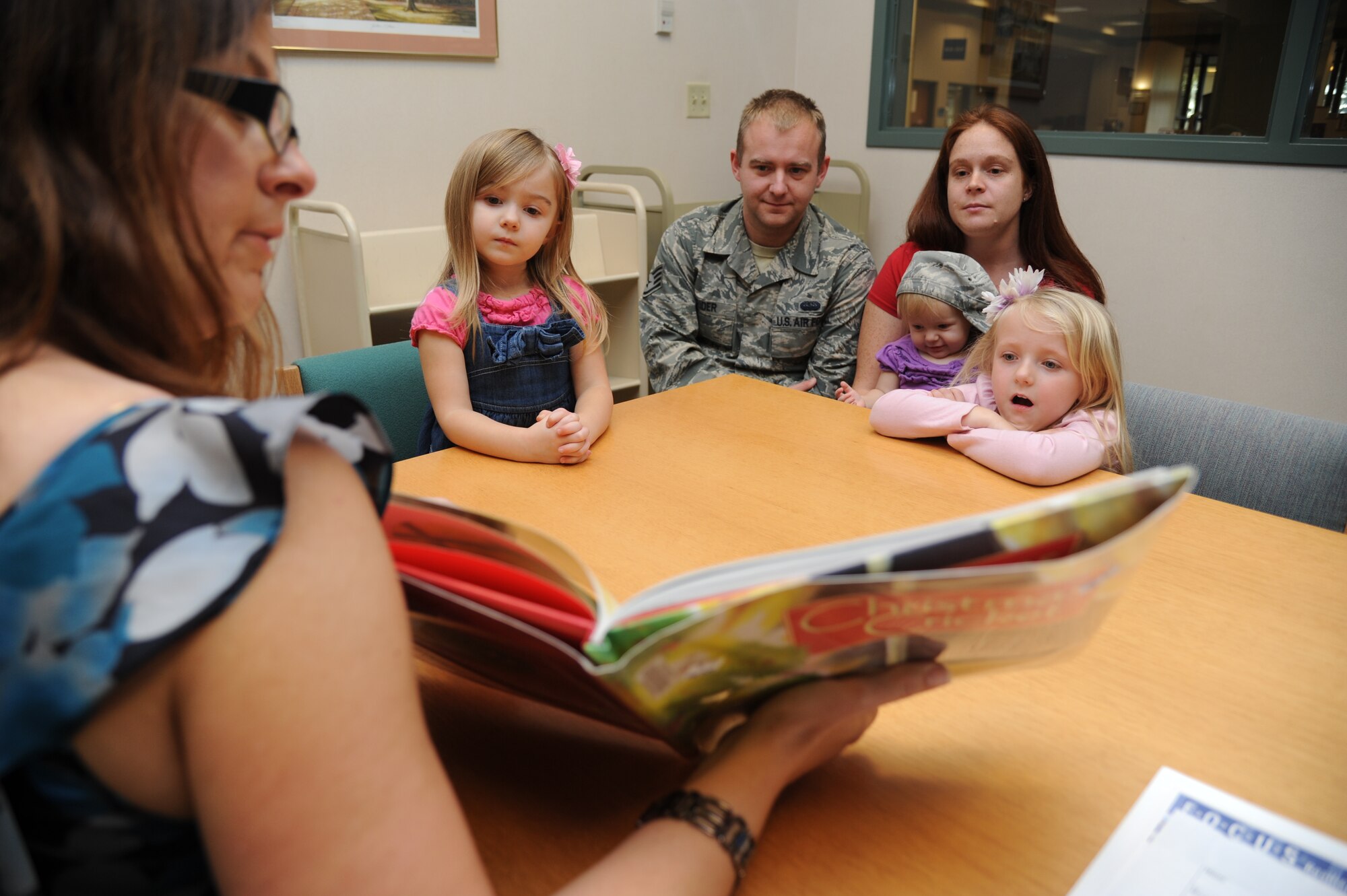 Kim Perez, a contractor with Families OverComing Under Stress, reads the book, The Christmas Cricket by Eve Bunting, to Natalie Crider, 3; her dad, Staff Sgt. Eric Crider, 333rd Training Squadron; mom, Barbara; sisters Jenna, 1, and Autumn, 5, during story time at the McBride Library Dec. 6, 2012, Keesler Air Force Base, Miss.  FOCUS leads resiliency training for military families.  (U.S. Air Force photo by Kemberly Groue)
