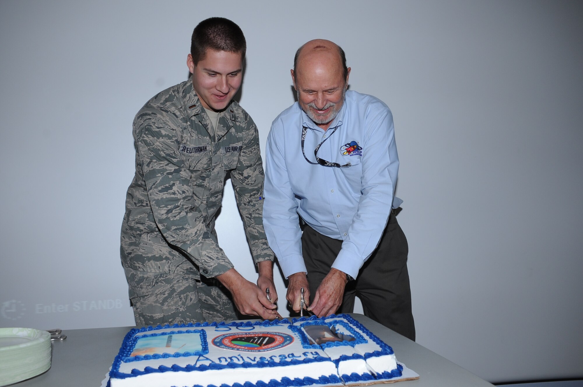 KIRTLAND AFB, N.M. -- During the Rocket Systems Launch Program's 50th anniversary party, conducted at the Phillips Space Conference Center Dec. 3, the newest and longest-standing unit members, 2nd Lt. Kevin Steuterman and John Wee, cut a cake to commemorate the milestone. The RSLP is administered by the Space Development and Test Directorate. (Courtesy photo)
