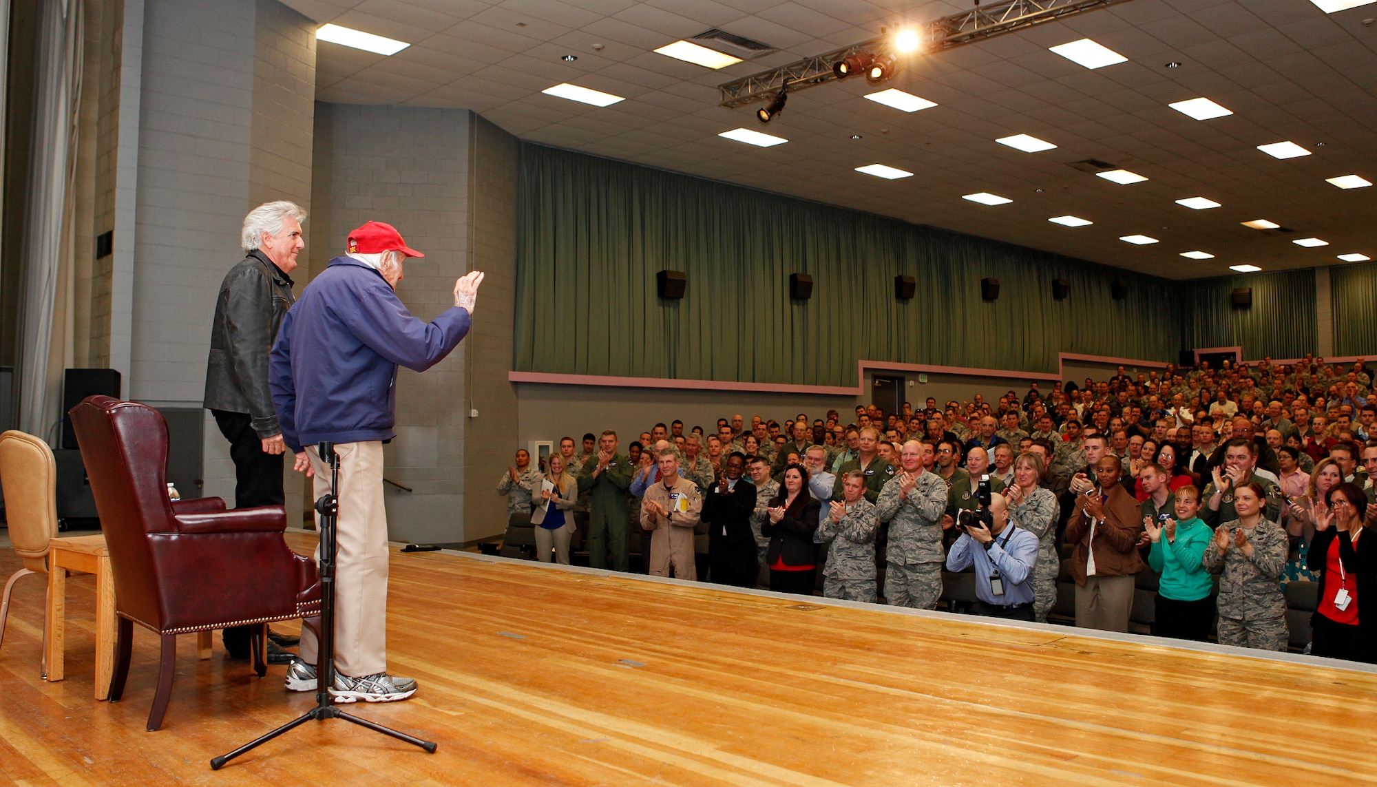 Louis Zamperini stands with his son, Luke, at the end of his presentation during resiliency training at the Base Theater, Dec. 10. (U.S. Air Force photo by Jet Fabara)