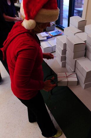 Phylis McComb, spouse of Col. Richard McComb, Joint Base Charleston Commander, ties a box during the Annual Cookie Drop Dec. 6, 2012, at the Joint Base Charleston - Air Base Chapel Annex. Operation cookie drop has been an Air Force tradition celebrated at bases around the world during the holiday season to show appreciation to war fighters overseas and young Airmen and Sailors living in the dorms, who are unable to be with their families during the holidays. This year’s Cookie Drop collected more than 500 boxes of homemade treats for dorm residents and enough treats to ship overseas for 140 deployed Airmen from JB Charleston. (U.S. Air Force photo/ Airman 1st Class Chacarra Walker)