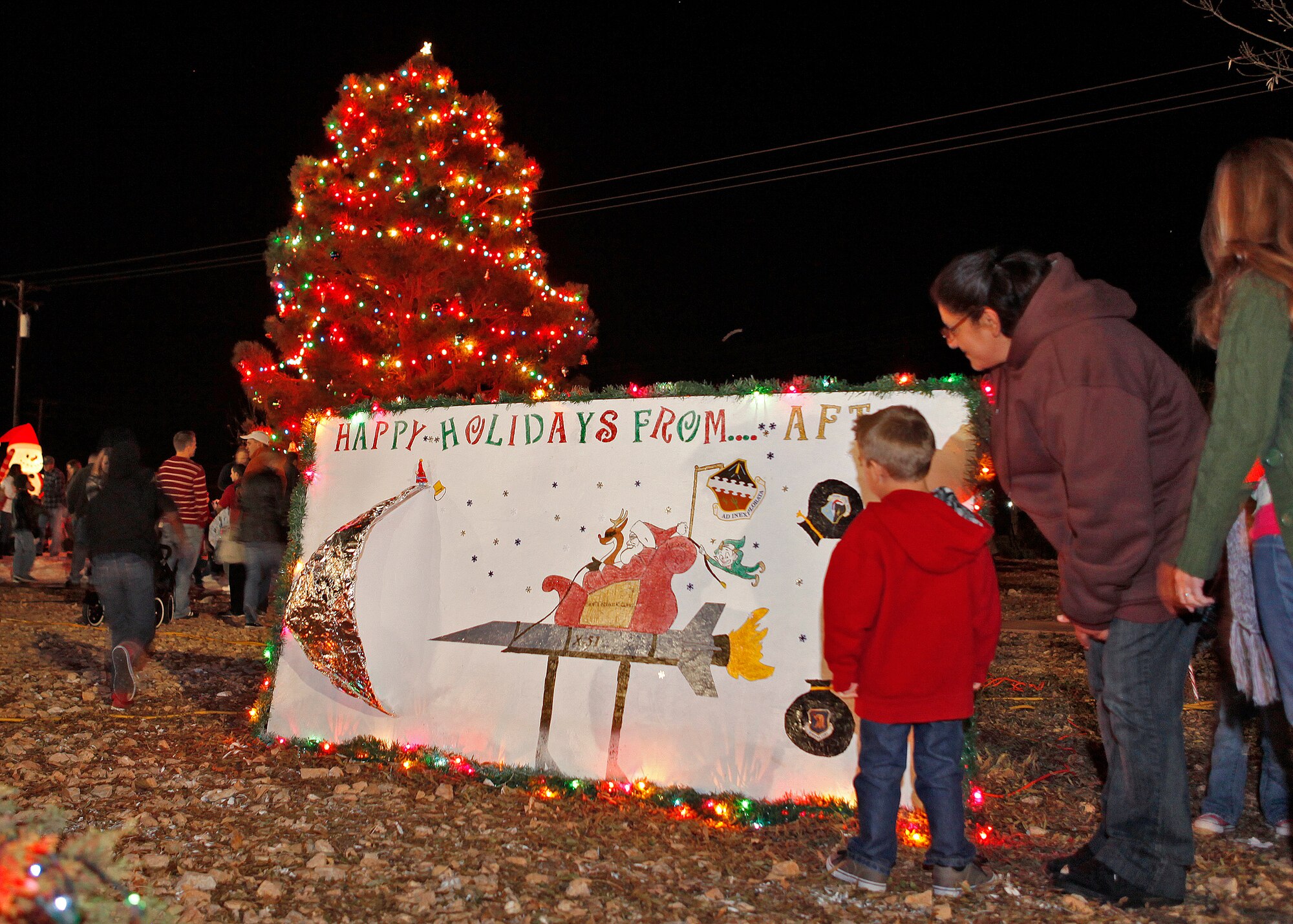Cathy Ramirez, dependent, shows her grandson one of the many holiday cards that were on display during the annual tree lighting ceremony held Dec. 7, 2012 in front of the Base Exchange. (U.S. Air Force photo by Jet Fabara)