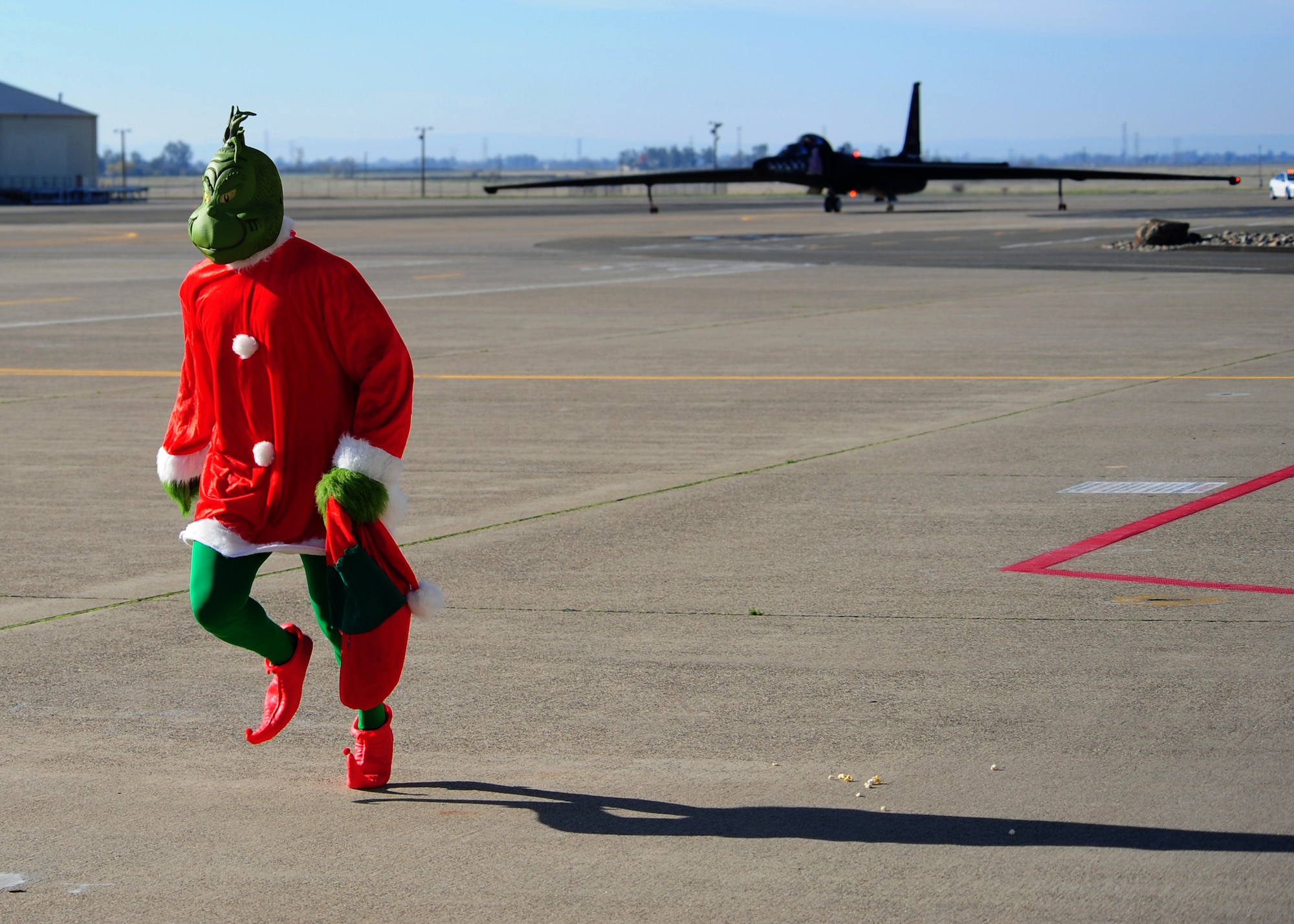 The Grinch runs away as Santa Claus taxis into Dock 6 riding in a themed U-2 Dragon Lady for the Children's Holiday Party Dec. 8, 2012, at Beale Air Force Base, Calif. After exiting the aircraft painted with holiday nose art, Beale youths excitedly surrounded St. Nick. (U.S. Air Force photo by Senior Airman Shawn Nickel/Released)