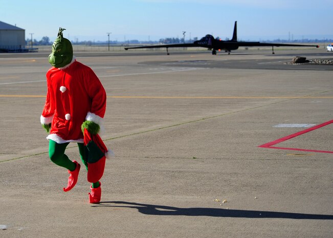 The Grinch runs away as Santa Claus taxis into Dock 6 riding in a themed U-2 Dragon Lady for the Children's Holiday Party Dec. 8, 2012, at Beale Air Force Base, Calif. After exiting the aircraft painted with holiday nose art, Beale youths excitedly surrounded St. Nick. (U.S. Air Force photo by Senior Airman Shawn Nickel/Released)