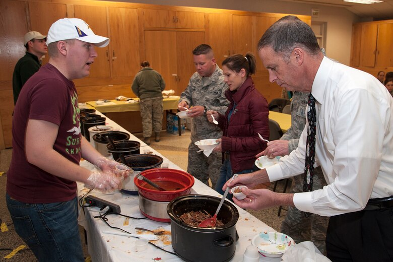 PETERSON AIR FORCE BASE, Colo. -- Airman 1st Class Andrew Revier (left), 21st Mission Support Group, serves chili to Tim Omdal (right), 21st Security Forces Squadron provost marshal, Nov. 28 at the base chapel. Participants sampled and voted for their favorite chili dish and made donations as part of a Combined Federal Campaign fundraiser. Tech. Sgt. Chris Whitfill, 21st Civil Engineer Squadron, took home trophies for best and hottest chili, as the contest raised $315 for the CFC. To donate to the CFC, see unit points of contact or go to https://www.cfcnexus.org/_peakcfc/. The deadline to turn in forms is Dec. 14. (U.S. Air Force photo/Craig Denton)