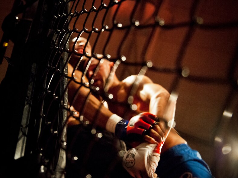 William “The Slim Reaper” Kuhn and Danny Ruiz grapple against the cage during the mixed martial arts main event at Strike Fight Dec. 8 at Eglin Air Force Base, Fla.  Ruiz, an Air Force Reserve staff sergeant with the 919th Special Operations Wing, won by unanimous decision in one of 11 matches held at the base’s first-ever MMA event.  The debut event drew approximately 775 people.  (U.S. Air Force photo/Samuel King Jr.)