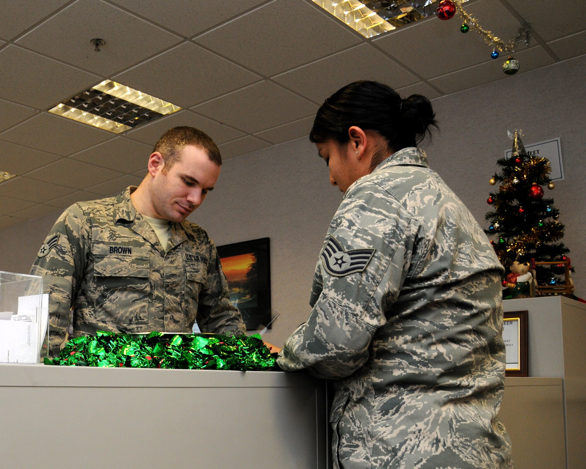 Senior Airman Jared Brown, 100th Force Support Squadron career development assignments and reenlistments journeyman from Midway, Ga., assists a customer with her extension paperwork Dec. 11, 2012, at RAF Mildenhall, England. The career development and reenlistments section also manages outgoing personnel and retainability. (U.S. Air Force photo by Gina Randall/Released)