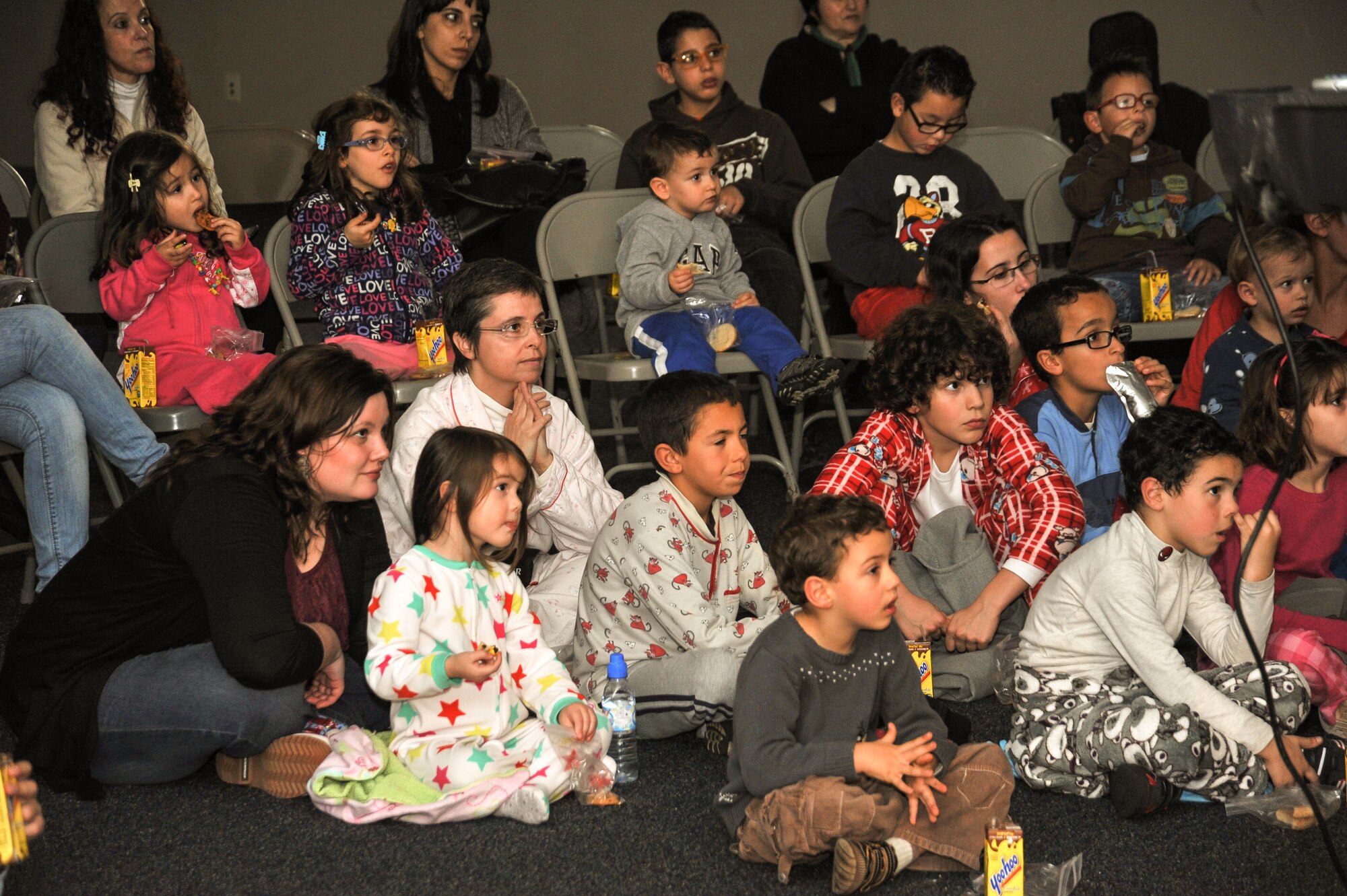 Maria David, wife of Tech. Sgt. Jason David, American Forces Network-Lajes, and overseas committee chair of the American Girl Scouts, sits with her daughter, Leinani, 3, as well as Cidalia Dias, leader of the Portuguese Girl Scouts, at the Community Activities Center Dec. 8. The Portuguese Girl Scouts as well as a local orphanage received a special invitation to experience "The Polar Express" on Lajes. (U.S. Air Force photo by Staff Sgt. Angelique N. Smythe)