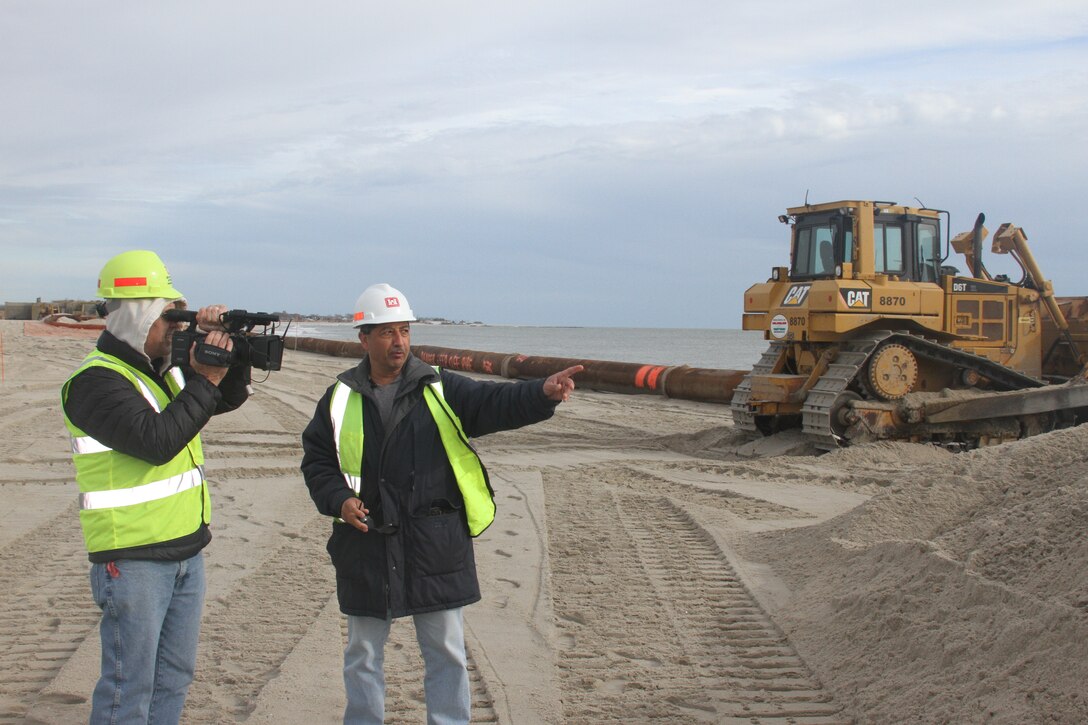 U.S. Army Corps of Engineers Philadelphia District Project Engineer Mandeep Talwar (right) explains ongoing work for the $8 million Lower Cape May Meadows beach renourishment project in December of 2012. Philadelphia District Videographer Richard Pearsall captures footage of the operation.  