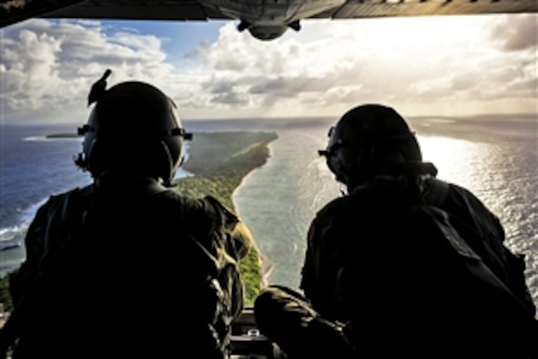 U.S. Air Force Senior Airman Timothy Oberman, left, and U.S. Air Force Staff Sgt. Nick Alarcon, right, watch out the back of a C-130H aircraft after dropping the first pallet of humanitarian goods to the island of Ulal, Dec. 11, 2012. Oberman and Alarcon, loadmasters, are assigned to the 36th Airlift Squadron, Yokota Air Base, Japan. Operation Christmas Drop is a nonprofit organization powered by volunteers from Andersen Air Force Base and the local Guam community.