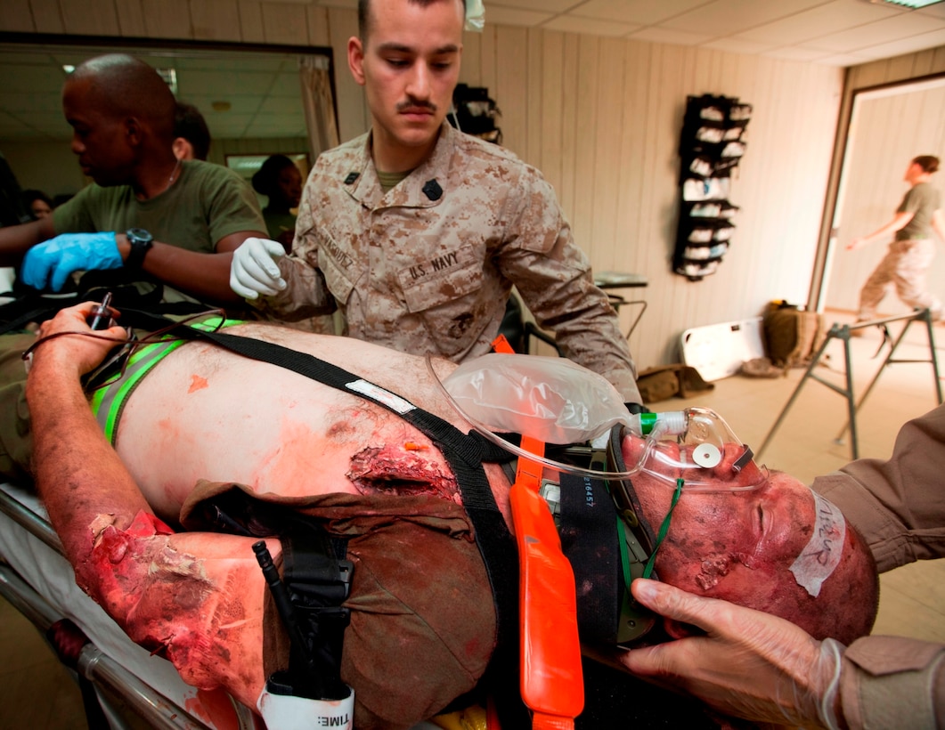 – Marine Aircraft Group 40 Navy Corpsmen, HM1 Francis Mungaithi and HN Nick Vasquez, treat HM1 (FMF) Edward Palakie for simulated sustained injuries produced by makeup during a trauma response exercise recently. MAG-40 currently assigned to U.S. Marine Corps Forces Central Command engages in Theater Security Cooperation activities throughout the U.S. Central Command area of responsibility and is prepared to provide rapid reaction to emerging crisis and contingency operations. (U.S. Marine photo by Sgt. Leon M. Branchaud )
