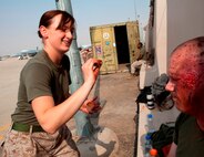 Marine Cpl. Elizabeth Deans, ambulance driver, Marine Aircraft Group 40 applies makeup and fake wounds to HM1 (FMF) Edward Palakie, corpsman, MAG-40, before a trauma response exercise recently. MAG-40 currently assigned to U.S. Marine Corps Forces Central Command engages in Theater Security Cooperation activities throughout the U.S. Central Command area of responsibility and is prepared to provide rapid reaction to emerging crisis and contingency operations. (U.S. Marine photo by Sgt. Leon M. Branchaud)
