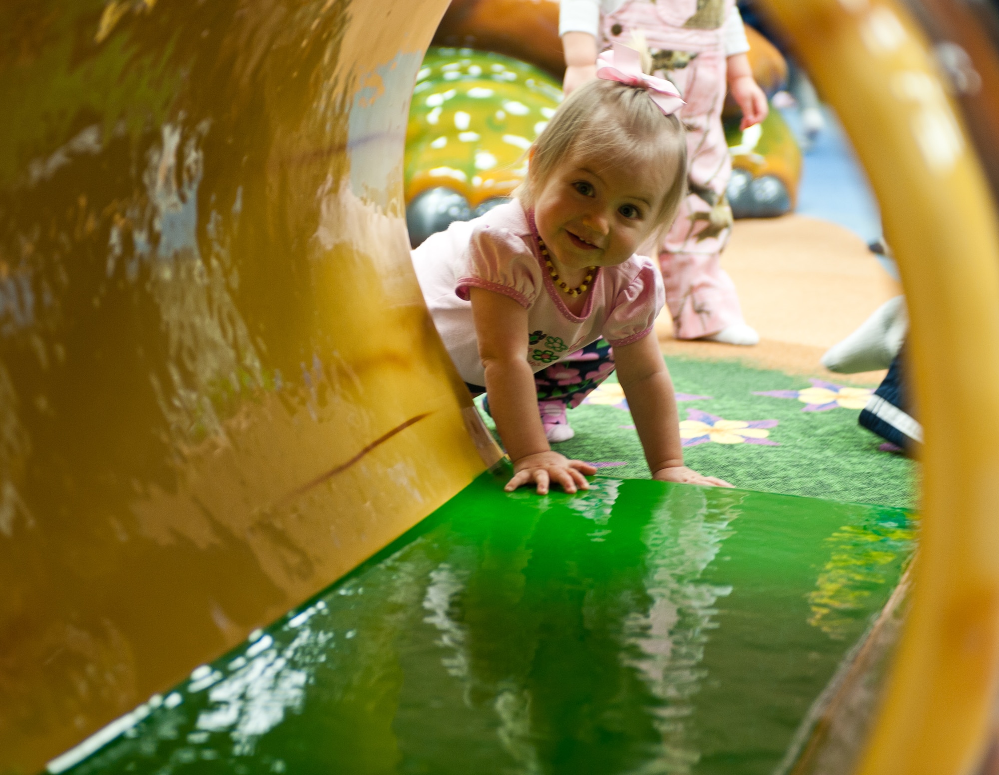 Genevieve Lance, 1, daughter of Maj. Robert Lance, 28th Civil Engineer Squadron operation flight commander, peeks through a sculpted log after the Safariland ribbon cutting in the Holbrook Library at Ellsworth Air Force Base, S.D., Dec. 7, 2012. The room is complete with safety pads on the walls and built-in memory games and mirrors at just the right height for little explorers. (U.S. Air Force photo by Airman 1st Class Alystria Maurer/Released)