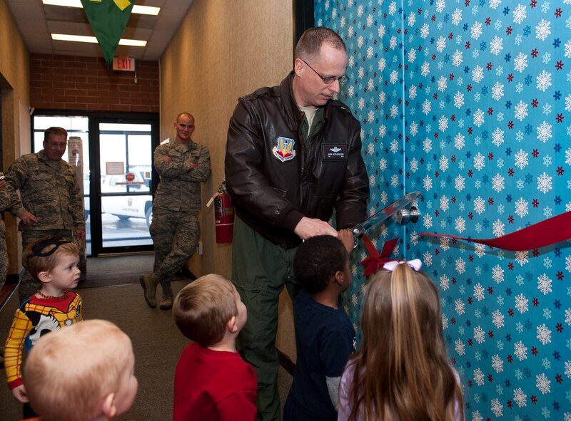 Col. Mark Weatherington, 28th Bomb Wing commander, cuts a ribbon with children at the Safariland play area in the Holbrook Library at Ellsworth Air Force Base, S.D., Dec. 7, 2012. The facility features carpet depicting scenes from the wilds of Africa, along with sculpted animals and a waterfall slide. (U.S. Air Force photo by Airman 1st Class Alystria Maurer/Released)