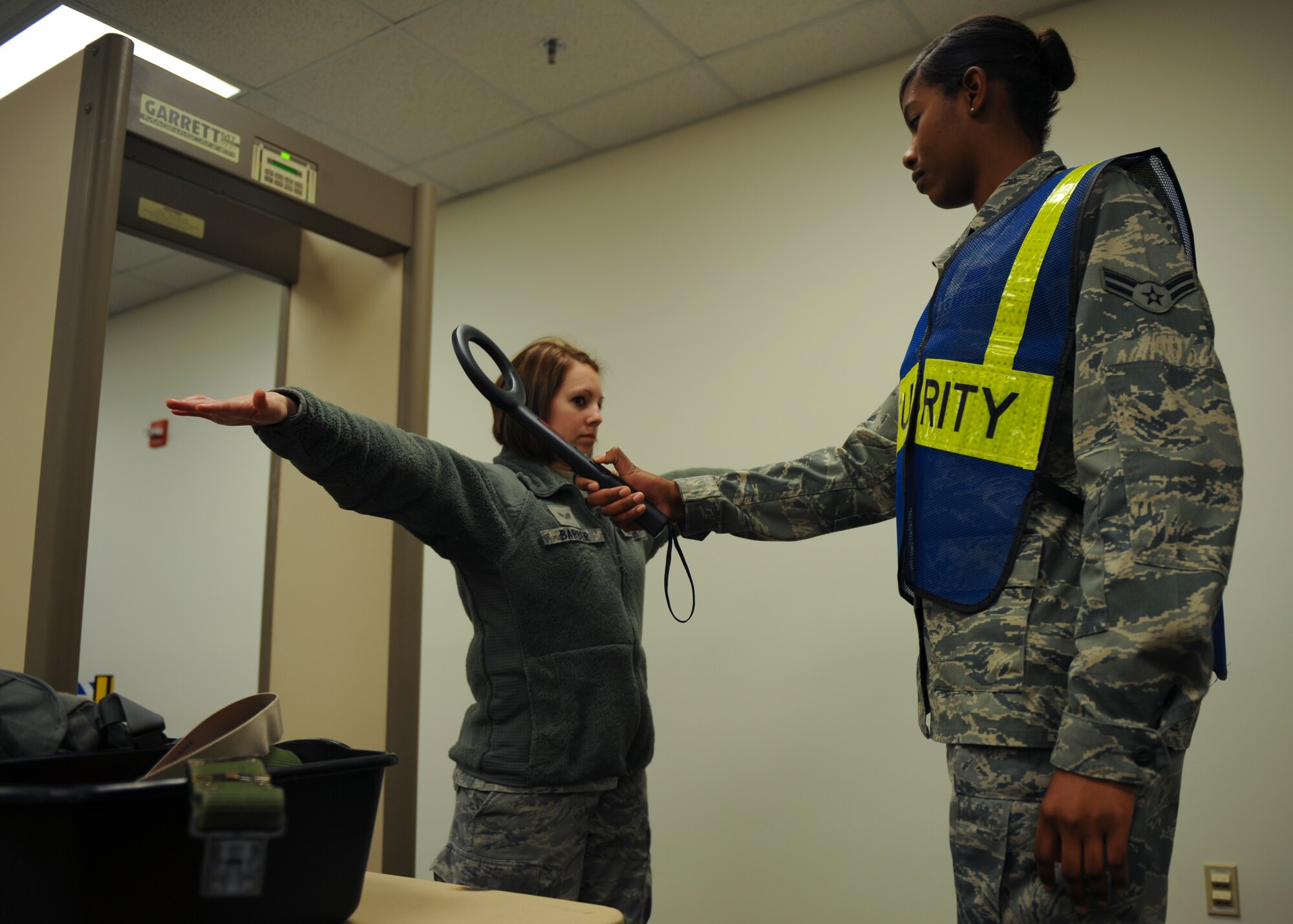 U.S. Air Force Airman 1st Class Karianna Mason, 633rd Force Support Squadron, scans Senior Airman Kristin Barber, 633rd Inpatient Operations Squadron, for weapons at the passenger terminal during the phase I combined unit exercise, at Langley Air Force Base, Va., Dec. 11, 2012. The CUE was held to validate the full spectrum of Langley's deployment operations. (U.S. Air Force photo by Staff Sgt. John D. Strong II/Released)