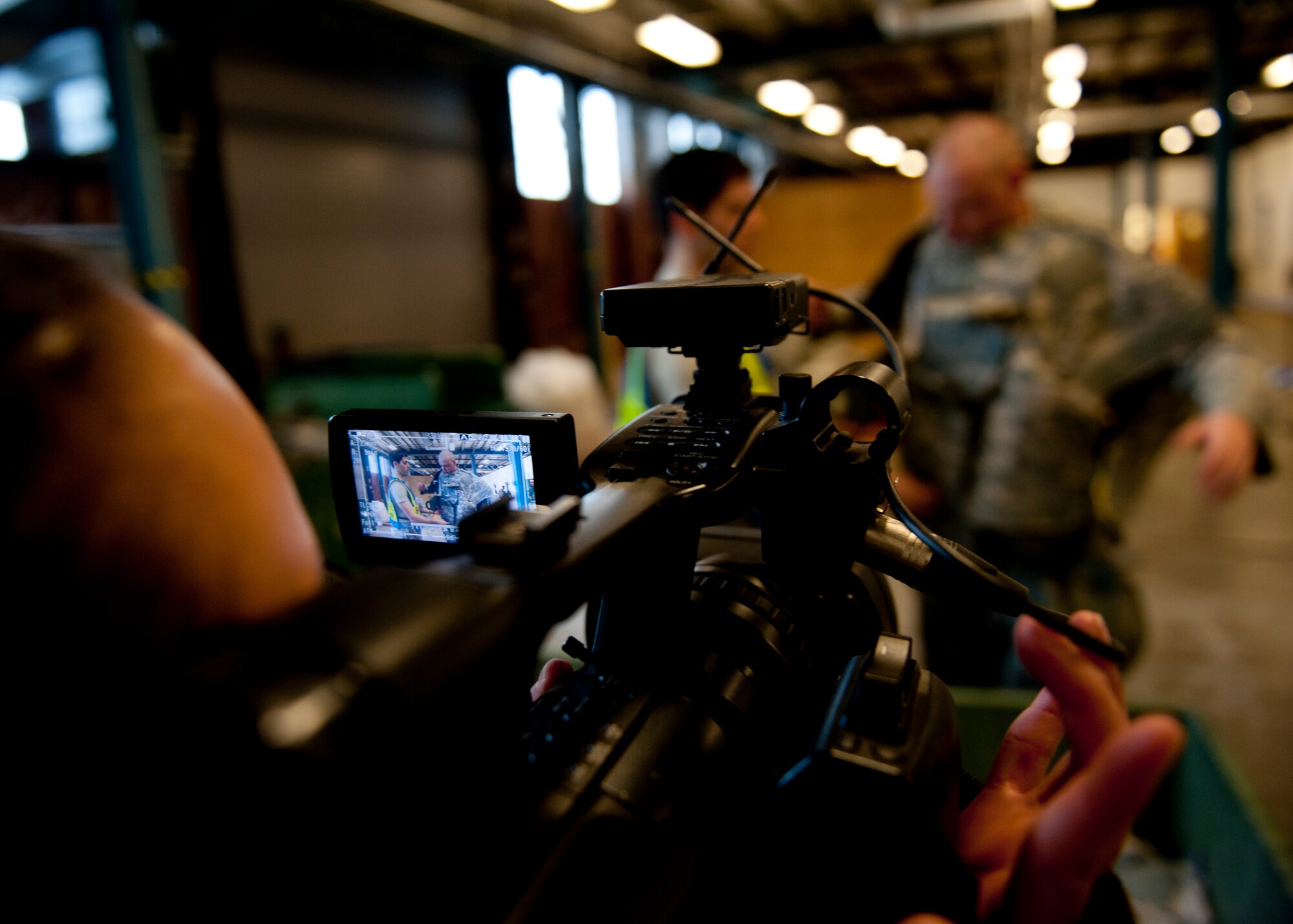 U.S. Air Force Airman 1st Class Tory Patterson, 633 Air Base Wing Public Affairs Office, records 2nd Lieutenant Michael Weaver, 633rd Logistics Readiness Squadron individual protective equipment officer in charge, fitting Airman 1st Class Benjamin Barker, 633rd Civil Engineer Squadron, structures apprentice, for individual body armor, during the phase I combined unit exercise at Langley Air Force Base, Va., Dec. 11, 2012.  The CUE was held to help Langley Airmen prepare for future deployments. (U.S. Air Force photo by Staff Sgt. John D. Strong II/Released)