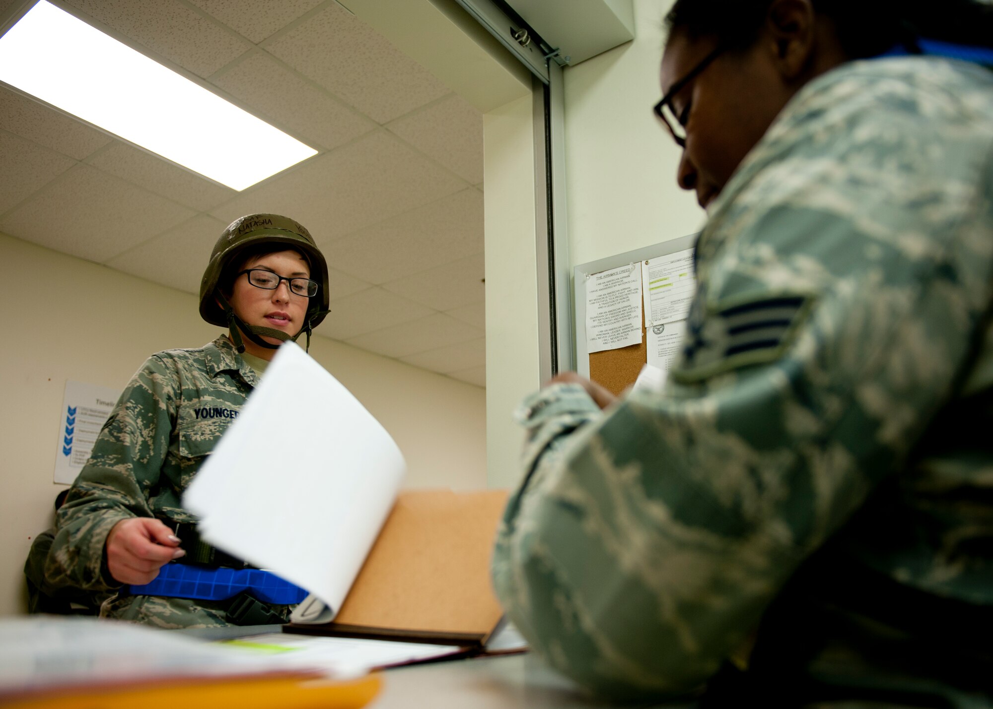 U.S. Air Force Airman 1st Class Natasha Younger, 633rd Medical Operations Squadron, out-processes with Senior Airman Airene Williams, 633rd Force Support Squadron, at the personnel deployment function line, during the phase I combined unit exercise, at Langley Air Force Base, Va. , Dec. 11. 2012.  The CUE was held to validate the full spectrum of Langley's deployment operations. (U.S. Air Force photo by Staff Sgt. John D. Strong II/Released)