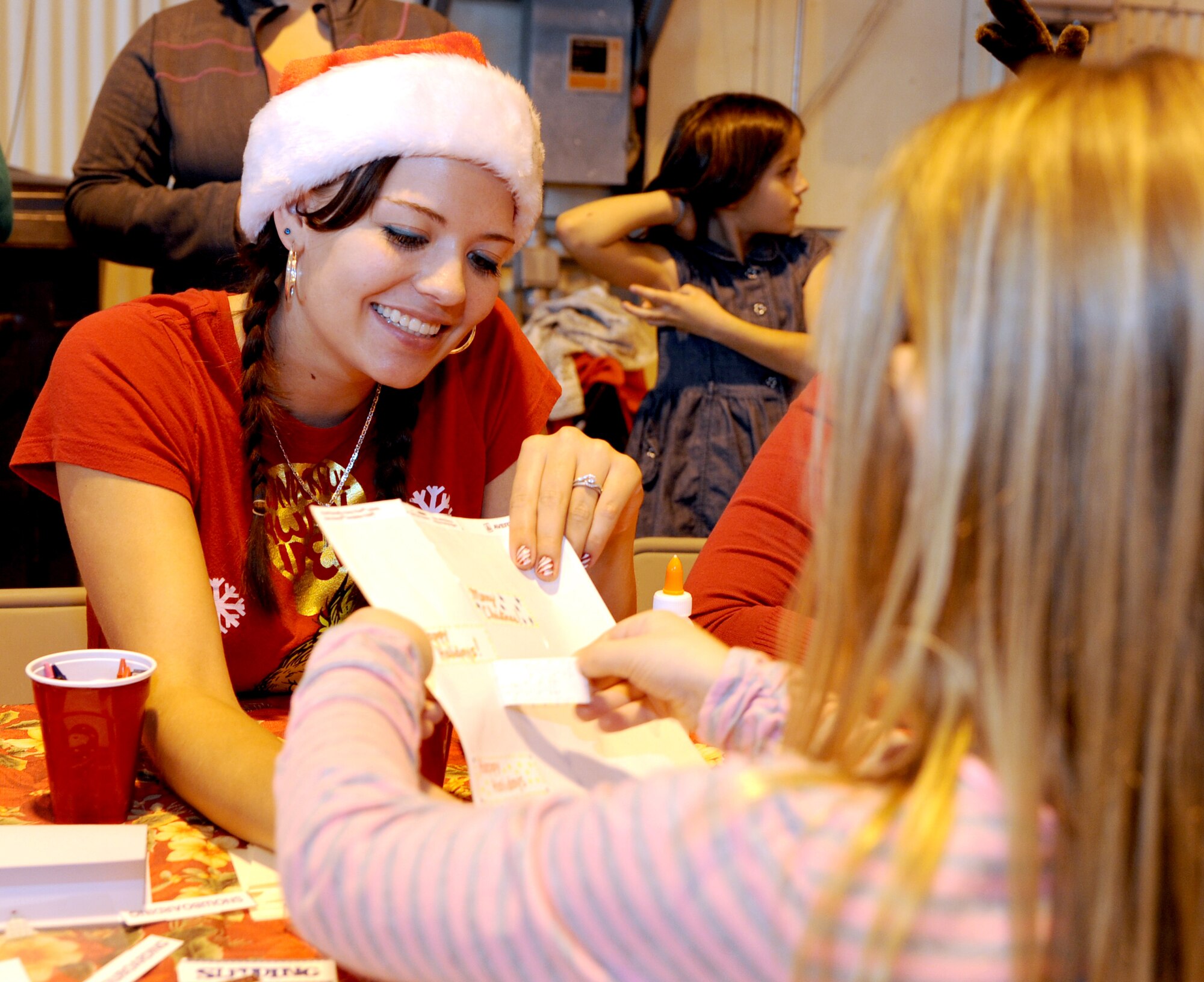 Alyissa Bartlett, wife of 2nd Lt. Jeremy Bartlett with the 71st Student Squadron, helps a girl with her Christmas card for Santa Claus during the Breakfast with Santa event held Dec. 1 in Hangar 170 at Vance Air Force Base, Okla. (U.S. Air Force photo/ Airman 1st Class Frank Casciotta)