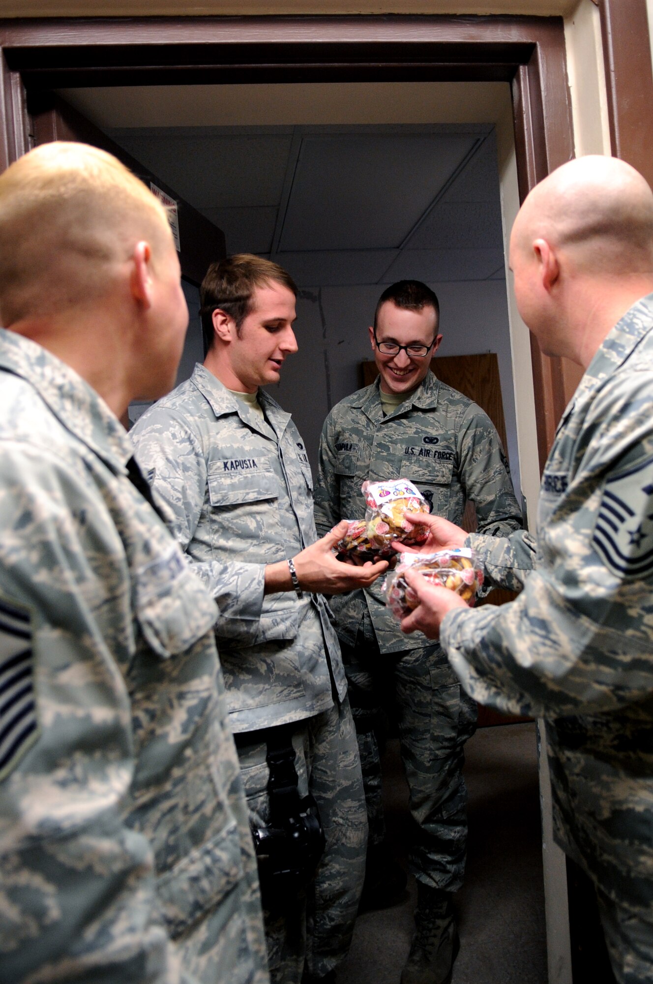 Senior Master Sgt. Brian Stone (left), 69th Reconnaissance Group first sergeant, and Master Sgt. Richard McCorkle (right), 319th Operations Support Squadron first sergeant, hand out cookie bags to Senior Airman Ian Kapusta and Airman 1st Class Alex Kumpula, 319th Security Forces Squadron, currently working at Cavalier Air Force Station, N.D., Dec. 10, 2012. Every year, the Grand Forks Air Force Base Spouses’ Club shows their appreciation by baking cookies and assembling cookie bags to surprise Airmen who live in the dorms.  This year, the Grand Forks Air Force Base First Sergeants’ Council delivered cookies to Airmen stationed on Cavalier Air Force Station and Grand Forks AFB, N.D. (U.S. Air Force photo/Staff Sgt. Amanda N. Grabiec)