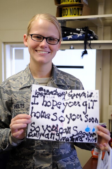 Airman 1st Class Amber Shelts, 319th Security Forces Squadron, displays a holiday card made by an elementary school student delivered by the Grand Forks Air Force Base, N.D., First Sergeants’ Council during their visit to drop off cookies Dec. 10, 2012, to Cavalier Air Force Station, N.D. Every year, the Grand Forks Air Force Base Spouses’ Club shows their appreciation to Airmen on base by baking cookies and assembling cookie bags to surprise Airmen who live in the dorms.  (U.S. Air Force photo/Staff Sgt. Amanda N. Grabiec)