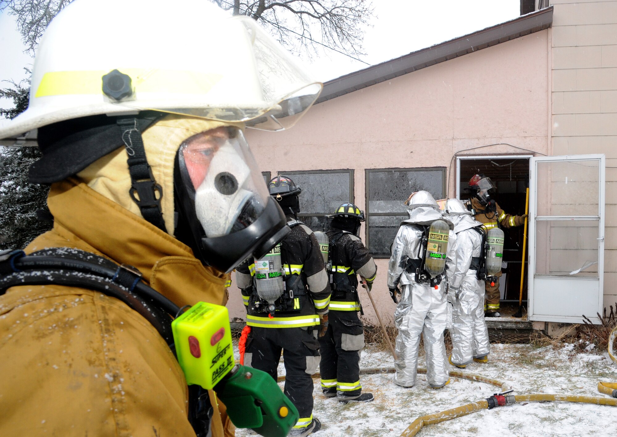 Larimore firefighters and Grand Forks Air Force Base, N.D., fire protection specialists position themselves to engage in a live fire fighting exercise Dec. 8, 2012, in Larimore, N.D.  The fire crews used a vacant residential home as the site for the joint military and civilian training which took approximately six hours to complete. (U.S. Air Force photo/Senior Airman Amber E. Bennett)