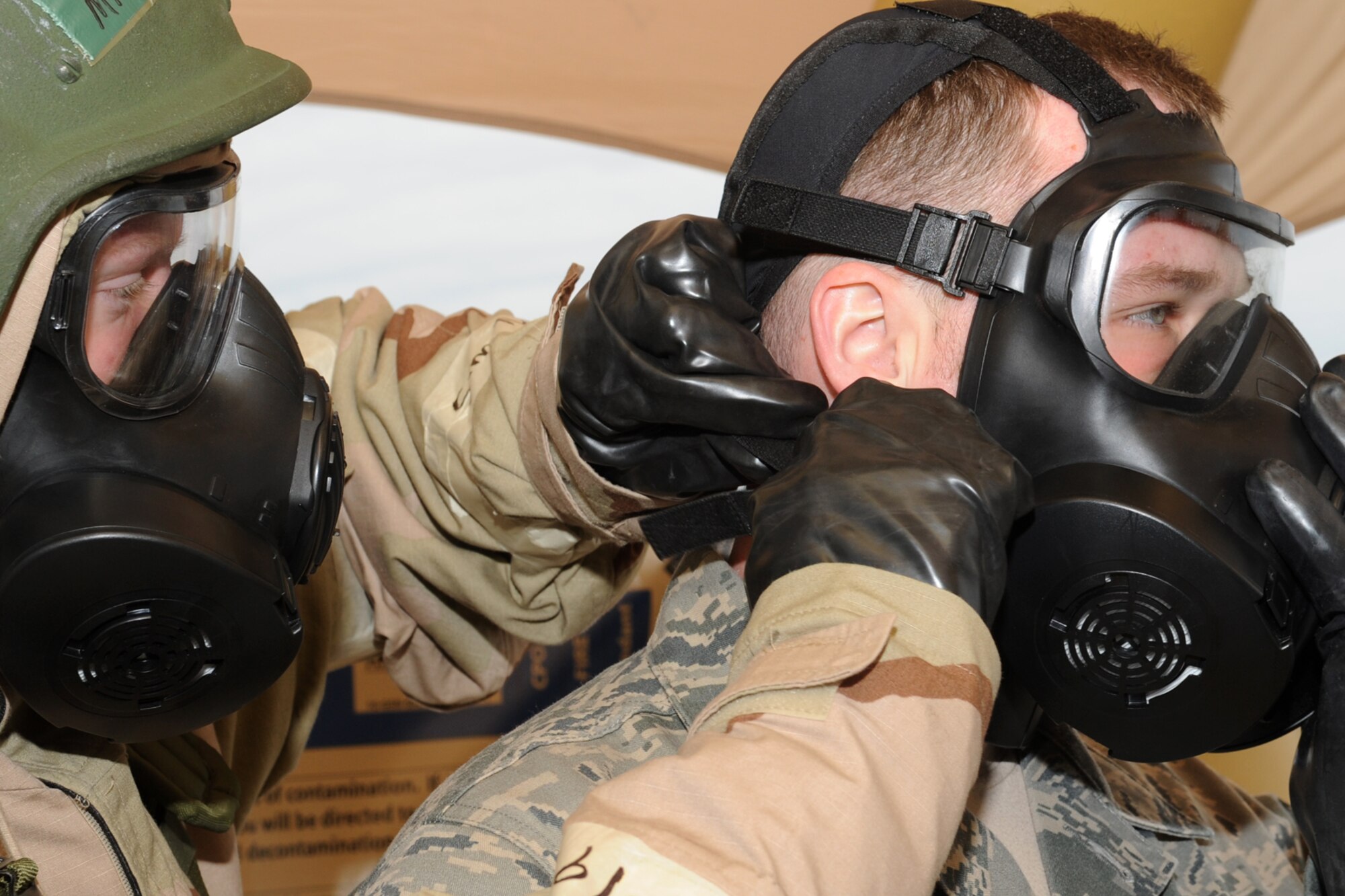 From left to right, U.S. Air Force Airman 1st Class Jerry Tondini, 633rd Security Forces Squadron installation entry controller, assists Staff Sgt. Daniel Zorko, 633rd Security Forces Squadron response force leader, with removing his gas mask during a combined unit exercise at Langley Air Force Base, Va., Dec. 12, 2012. The chemical decontamination process experience instructed Airmen how to successfully remove their mission orientated protective posture gear after a simulated chemical attack. (U.S. Air Force photo by Senior Airman Racheal E. Watson/Released)