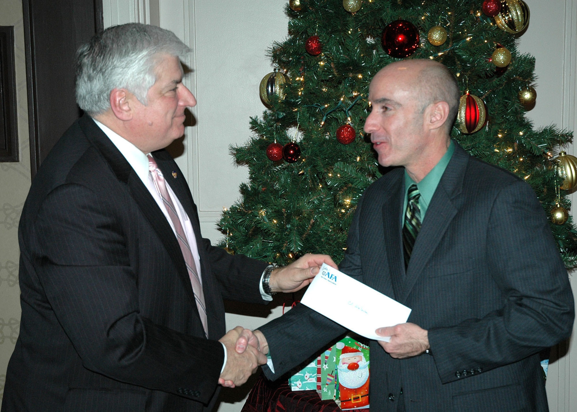 BEDFORD, Mass. – Col. Lester A. Weilacher, 66th Air Base Group commander, accepts a check for $5,000 from Paul Zauner, Air Force Association Paul Revere Chapter treasurer, during the AFA holiday party at the Bedford Glen DoubleTree hotel Dec. 7. The money, raised during the Veterans Day Fun Run, will be used to support deployed servicemembers and their families. (U.S. Air Force photo by James Corcoran)