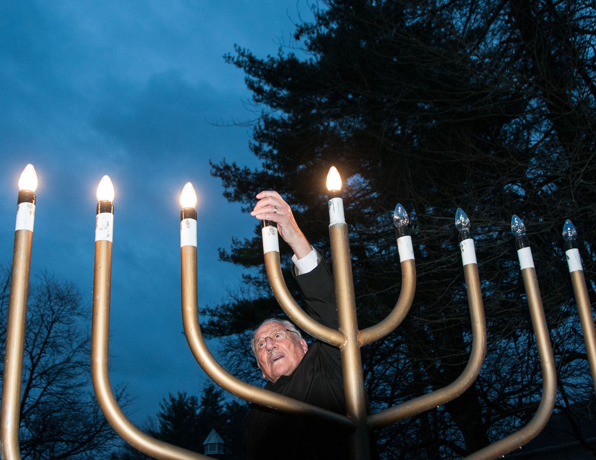 HANSCOM AIR FORCE BASE, Mass. -- Rabbi Abraham Morhaim lights the Menorah during a ceremony celebrating Hanukkah, the Jewish Festival of Lights, outside the chapel Dec. 10. The Jewish community hosted the Menorah Lighting Ceremony in celebration of the holiday which runs from Dec. 8 through Dec. 16. (U.S. Air Force photo by Walter Santos)
