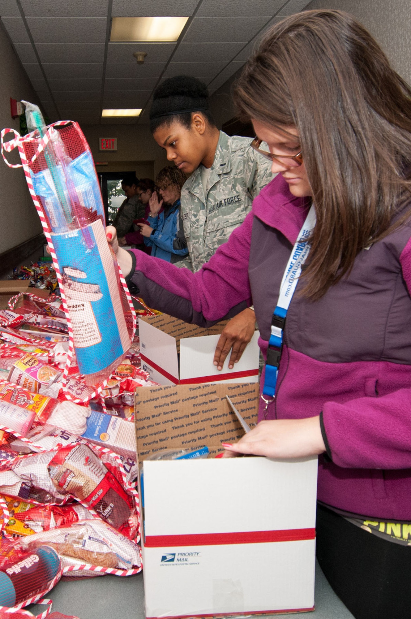 HANSCOM AIR FORCE BASE, Mass. -- Audrey Snow-Brine and 1st Lt. Dana Loveless place items in packages during the Company Grade Officers Council Troop Care Drive at the Minuteman Thrift Shop Dec. 5. The CGOC, along with many volunteers, were able to assemble more than 160 packages of much-needed items to send to deployed troops from Hanscom and neighboring units in the New England area (U.S. Air Force photo by Rick Berry)