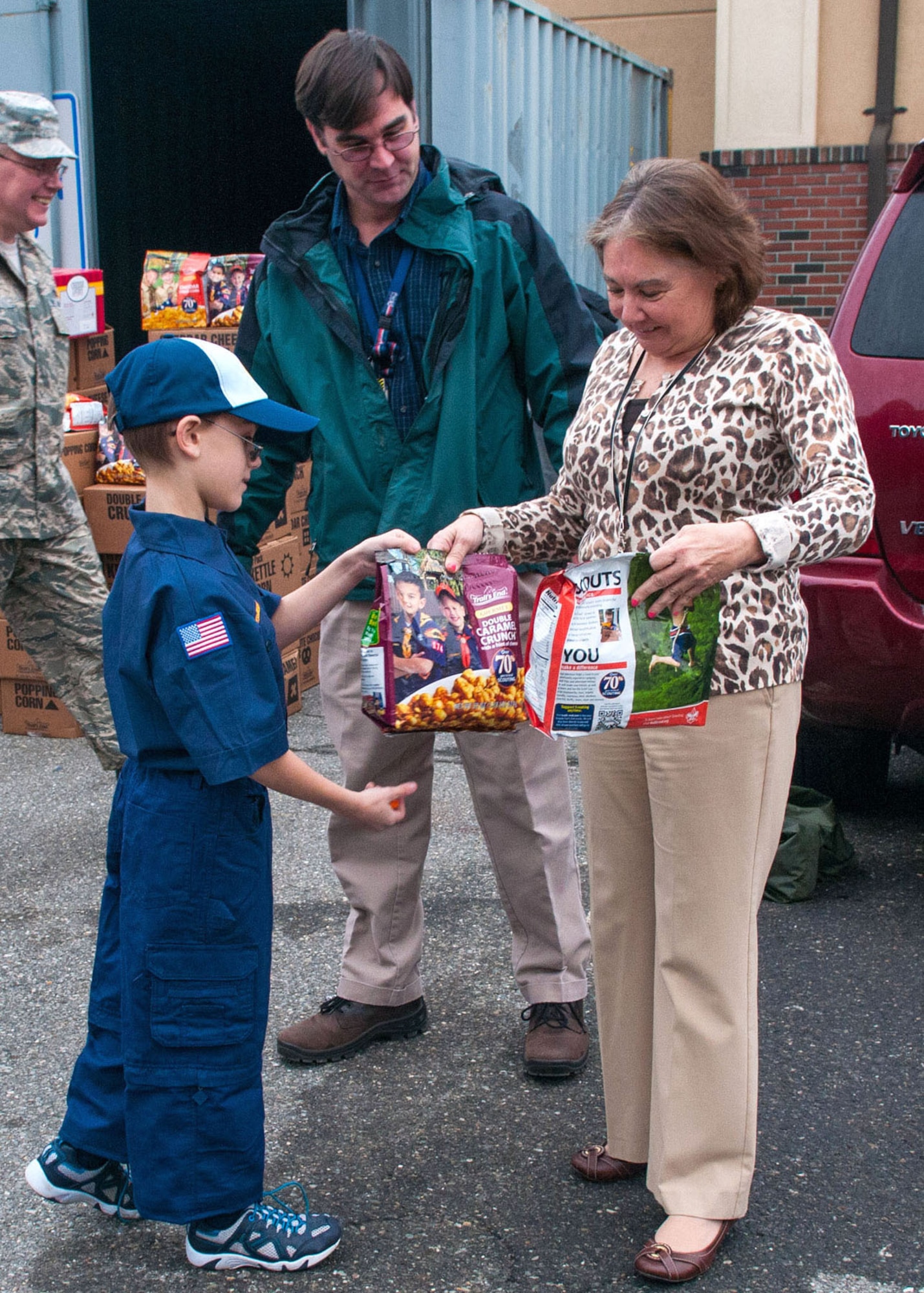 HANSCOM AIR FORCE BASE, Mass. -- Joshua Delory, from Cub Scout Troop 173, gives Carol Hoffses popcorn as part of a larger donation outside the Minuteman Thrift Shop Dec. 4. The local Cub Scout troop made the donation to the Company Grade Officers Council Troop Care Drive. (U.S. Air Force photo by Rick Berry)