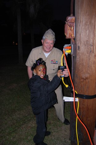 Capt. Thomas Bailey, Joint Base Charleston deputy commander, lights the Holiday tree with Zoe Johnson, daughter of Army SGT. Derrick Johnson, Dec. 13, 2012, at Joint Base Charleston – Weapons Station, S.C.  (Courtesy photo)  