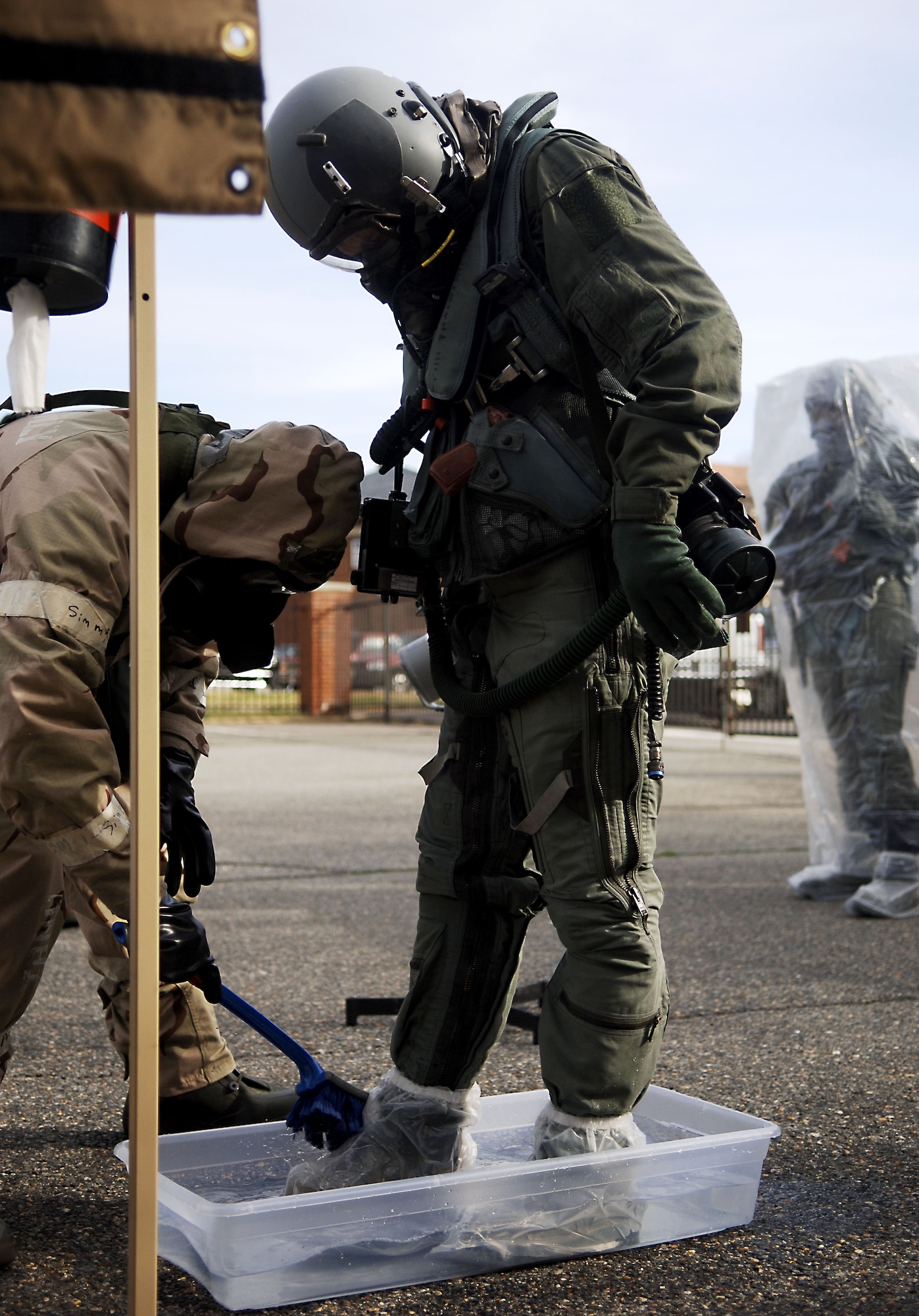 Aircrew flight equipment technicians with the 1st Operations Support Squadron conduct a pilot de-contamination exercise at Langley Air Force Base, Va., Dec. 7, 2012.  The aircrew de-contamination process consists of various stations, including weapons cleaning, misting and equipment removal.  (U.S. Air Force photo by Staff Sgt. Katie Gar Ward / Released)