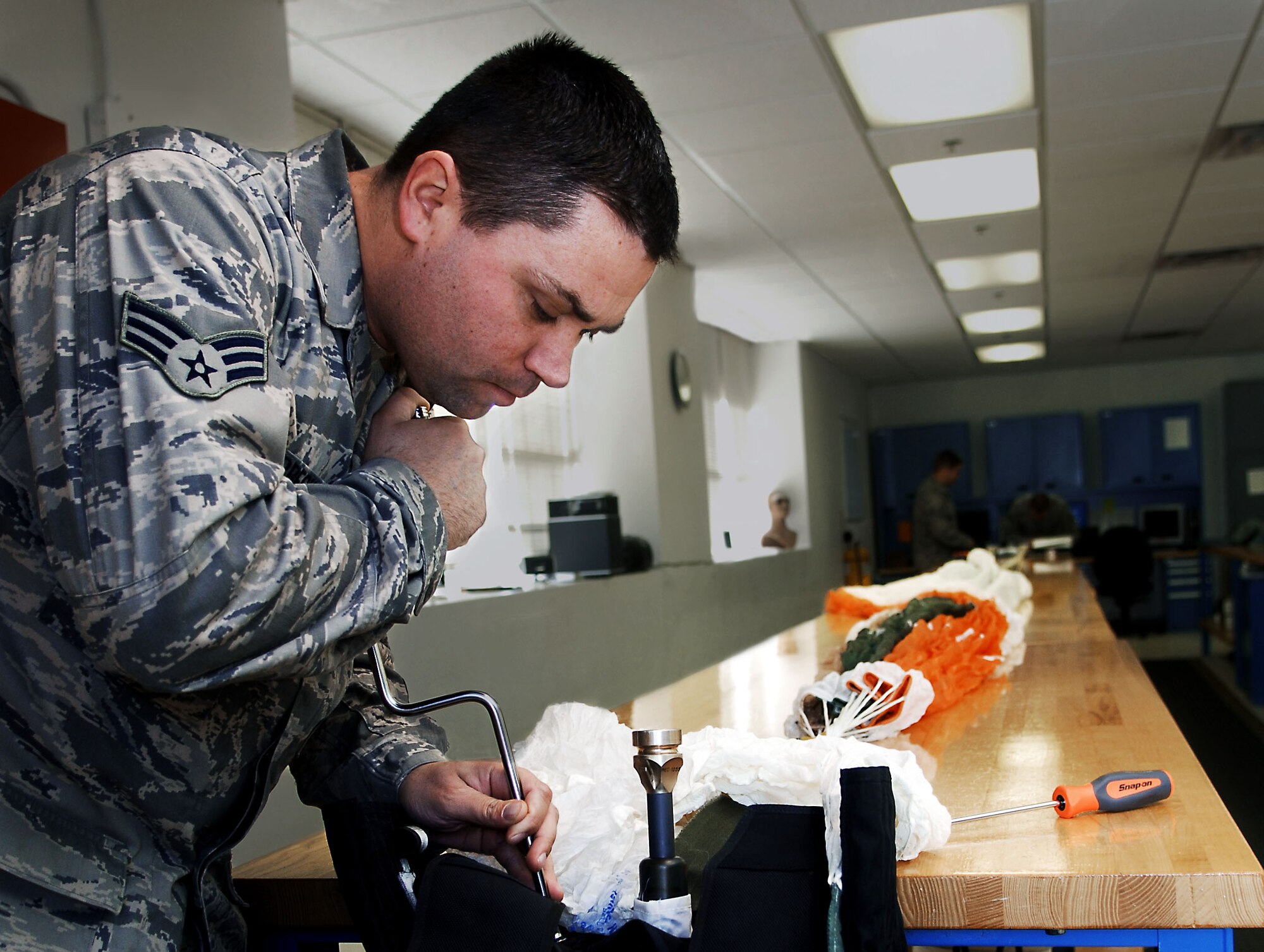 Senior Airman Roland Sperbeck, survival aircrew flight equipment technician with the 1st Operations Support Squadron, begins an in-progress inspection of an Aces II parachute at Langley Air Force Base, Va., Dec. 3, 2012.  These parachutes have a one-year repack cycle, and a full inspection can take up to four hours to complete. (U.S. Air Force photo by Staff Sgt. Katie Gar Ward / Released)  