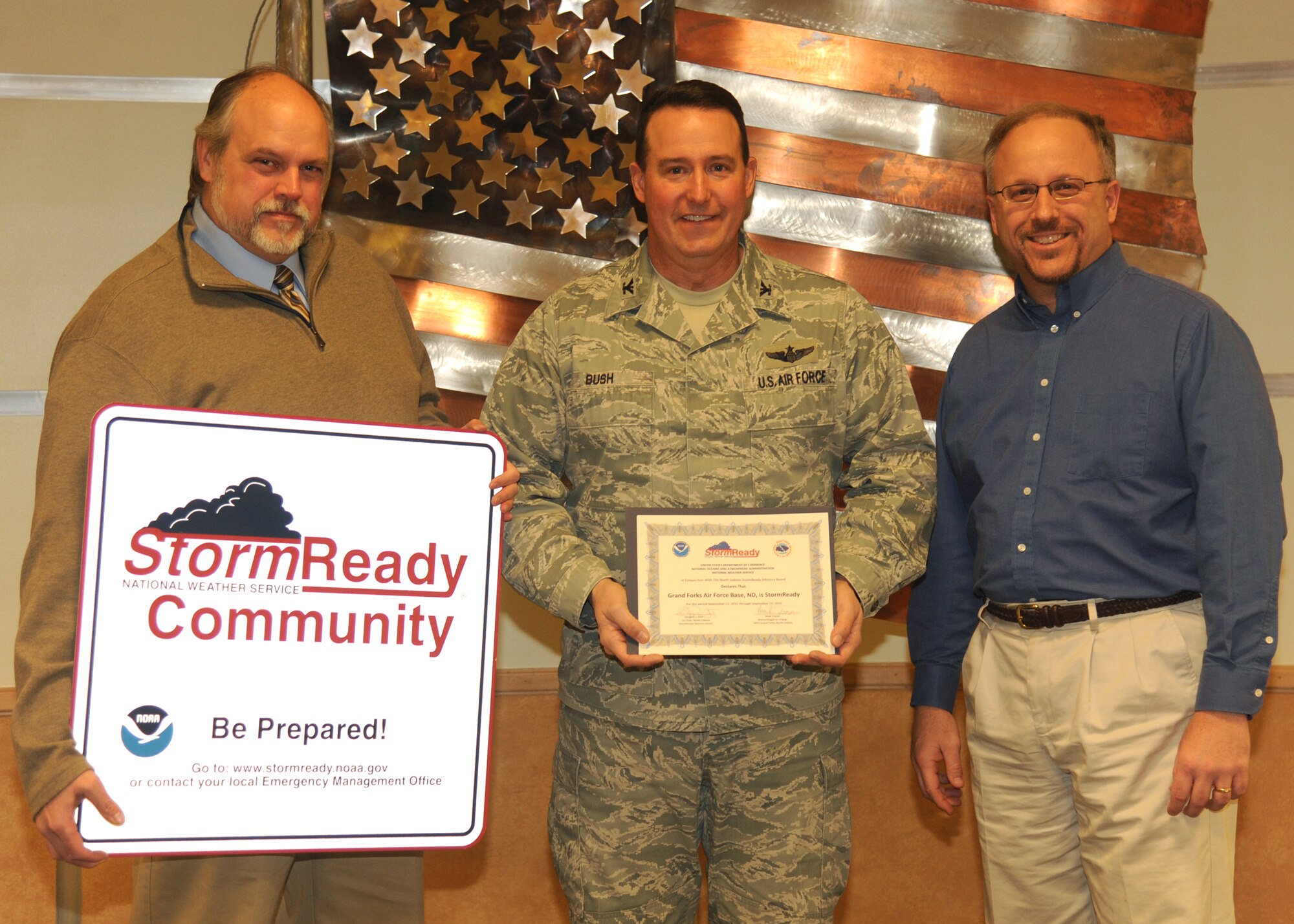 Greg Gust (left), warning coordinator meteorologist, and Mark Frazier (right), meteorologist-in-charge, both from the National Weather Service, present Col. Tim Bush, 319th Air Base Wing commander, with a certificate by the NWS on Dec. 10, 2012, on Grand Forks Air Force Base, N.D.  Grand Forks AFB was recently certified as StormReady by the NWS.  The Storm Ready program is designed to help arm communities with the communication and safety skills needed to save lives and property before and during a severe weather event.  Grand Forks AFB is currently the only military installation certified as Storm Ready in the state of North Dakota and one of three bases designated as such in Air Mobility Command.  (U.S. Air Force photo/Airman 1st Class Xavier Navarro)